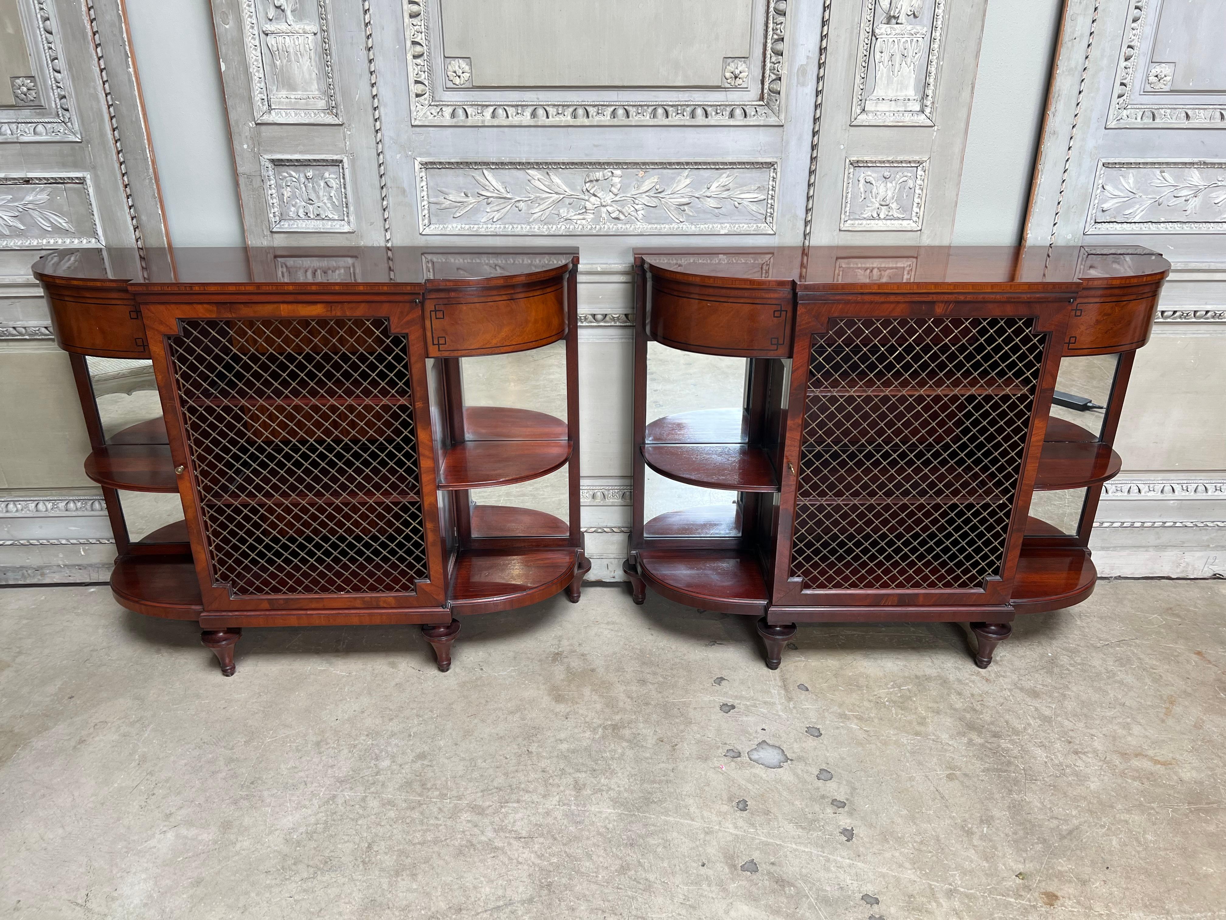 A pair of English Regency style mahogany buffets made by Beacon Hill Collection circa 1945. 
This fine pair of parquetry mahogany servers have a center door with brass grill and shelves flanked by open curved ends with mirrored backs.  They are