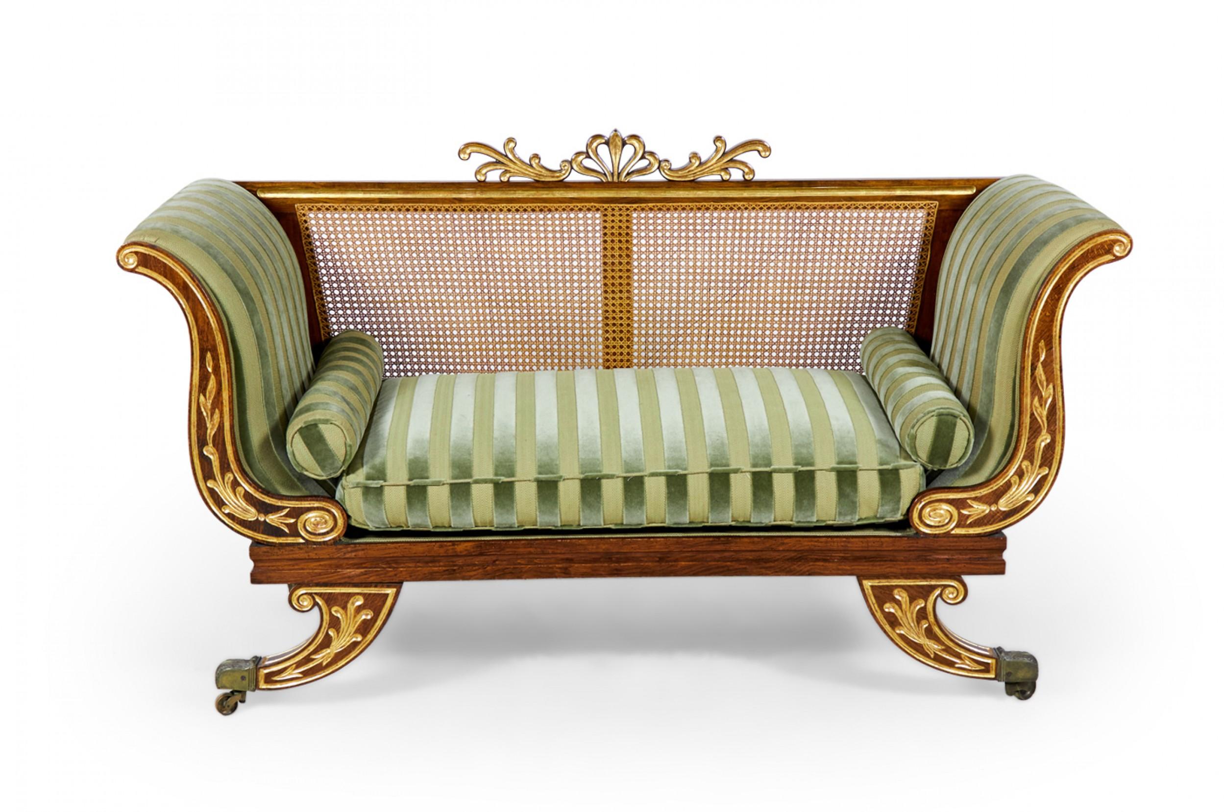 Pair of English Regency faux painted rosewood loveseats with parcel gilt ornaments, removable caned backs with gilt anthemion top crests, and mint green striped upholstery, resting on four curved legs ending in brass casters. (Priced as pair).