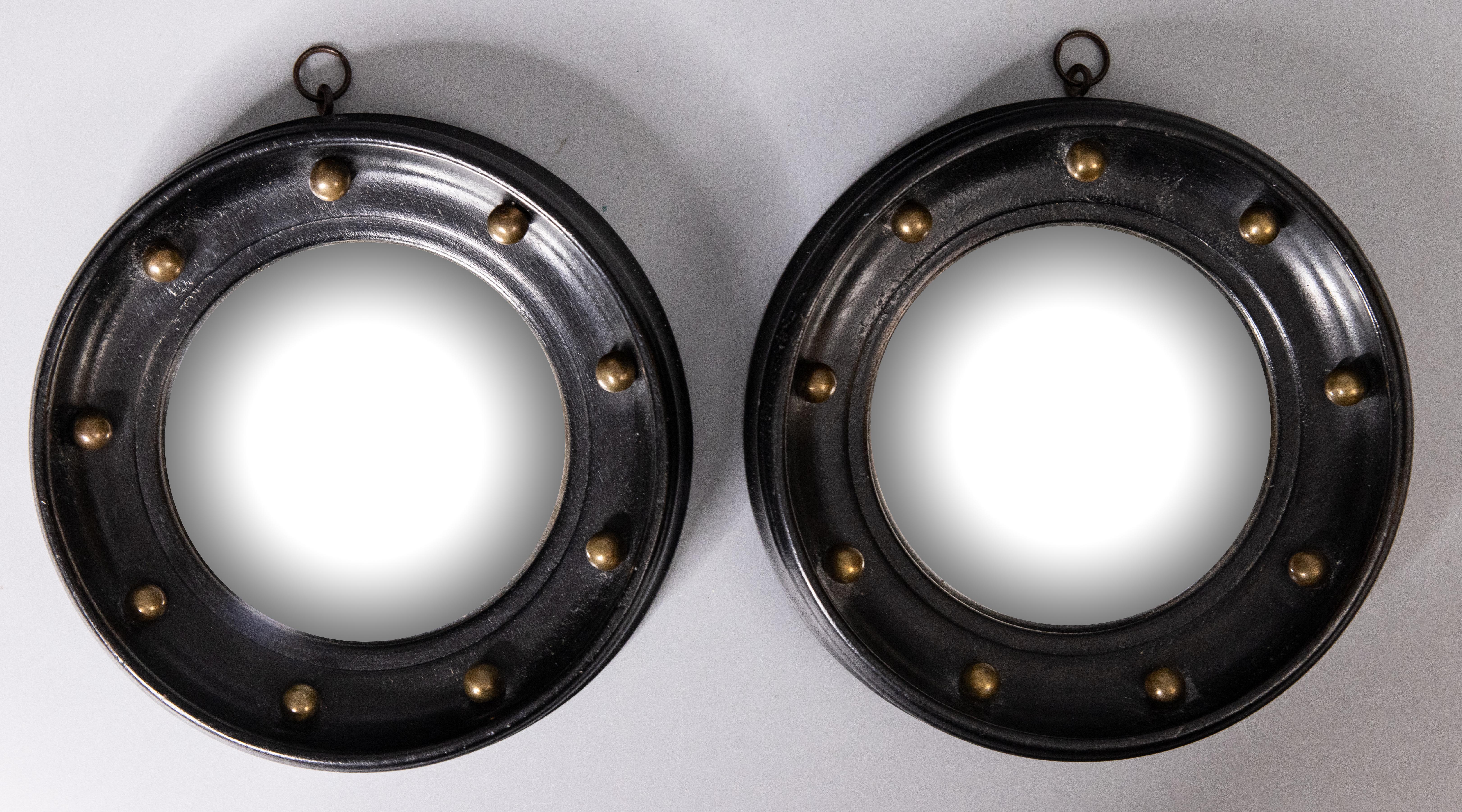 A superb pair of early Regency style black ebonized bullseye convex mirrors from England, circa 1910. These stunning mirrors are a charming petite size and retain the original convex mirror glass. They have turned ebonized frames accented with