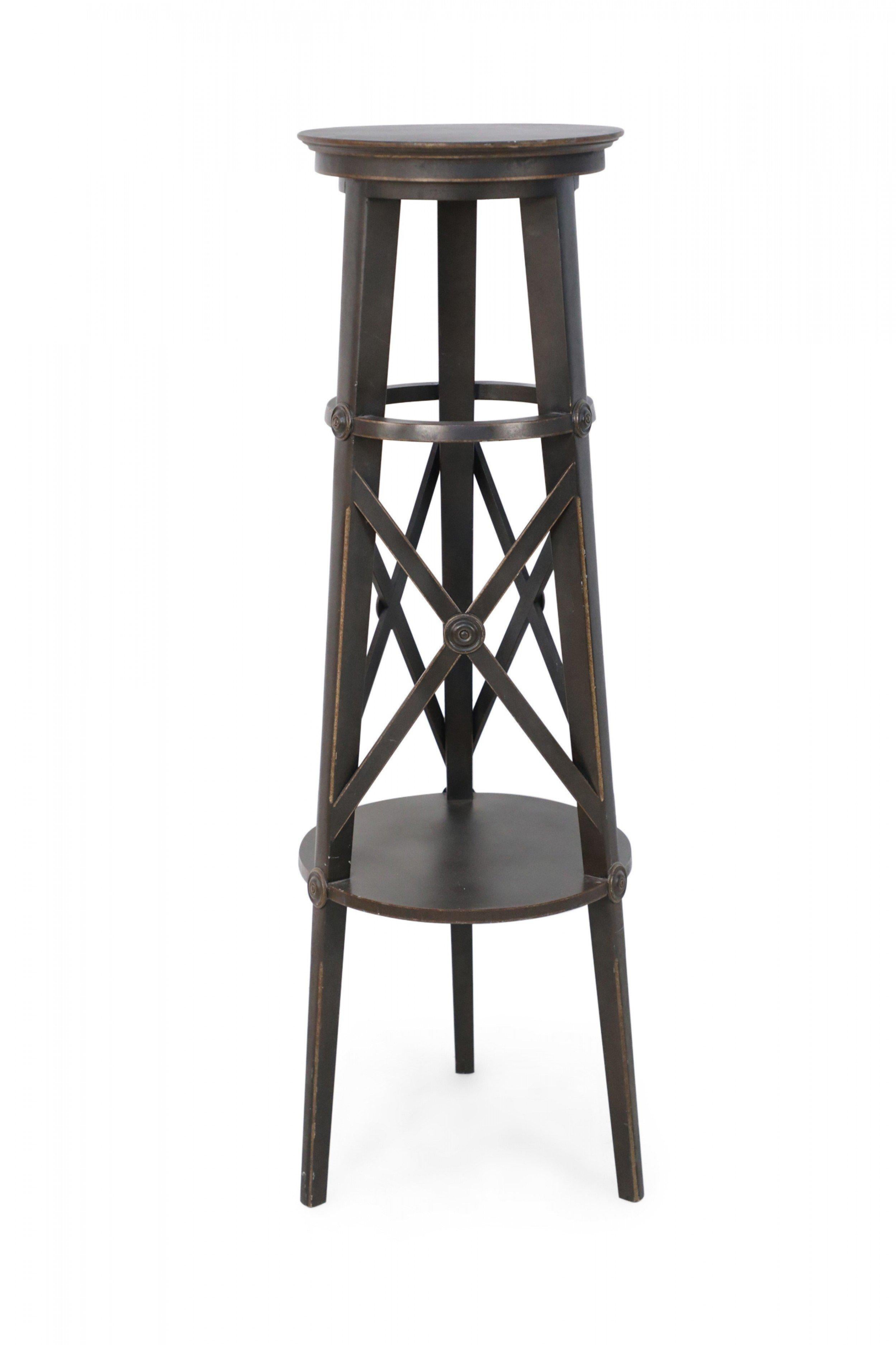 PAIR of tall circular brown painted wooden pedestals with top and bottom shelves connected by three legs with x-shaped supports, featuring carved circular medallions to emphasize where the lines intersect. (PRICED AS PAIR)