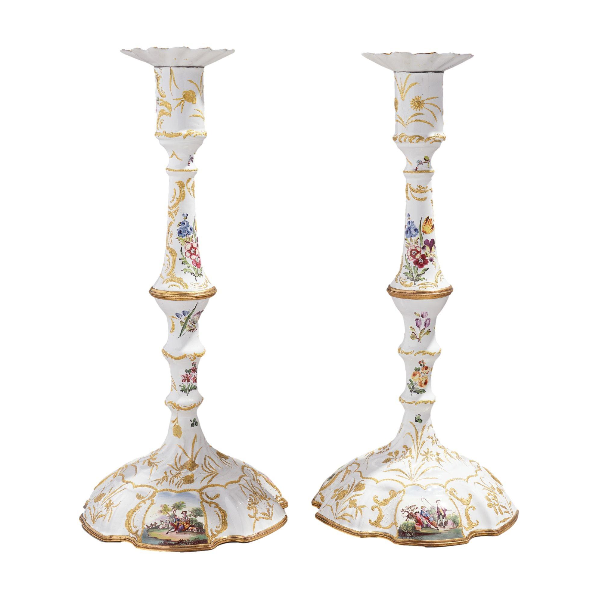 Pair of rare and exceptionally tall polychrome decorated Rococo Battersea candlesticks. The pair features a white enamel ground over copper, and the knobbed candle shaft, bobeche, and hexagonal lobed base feature hand painted with transfer vignettes