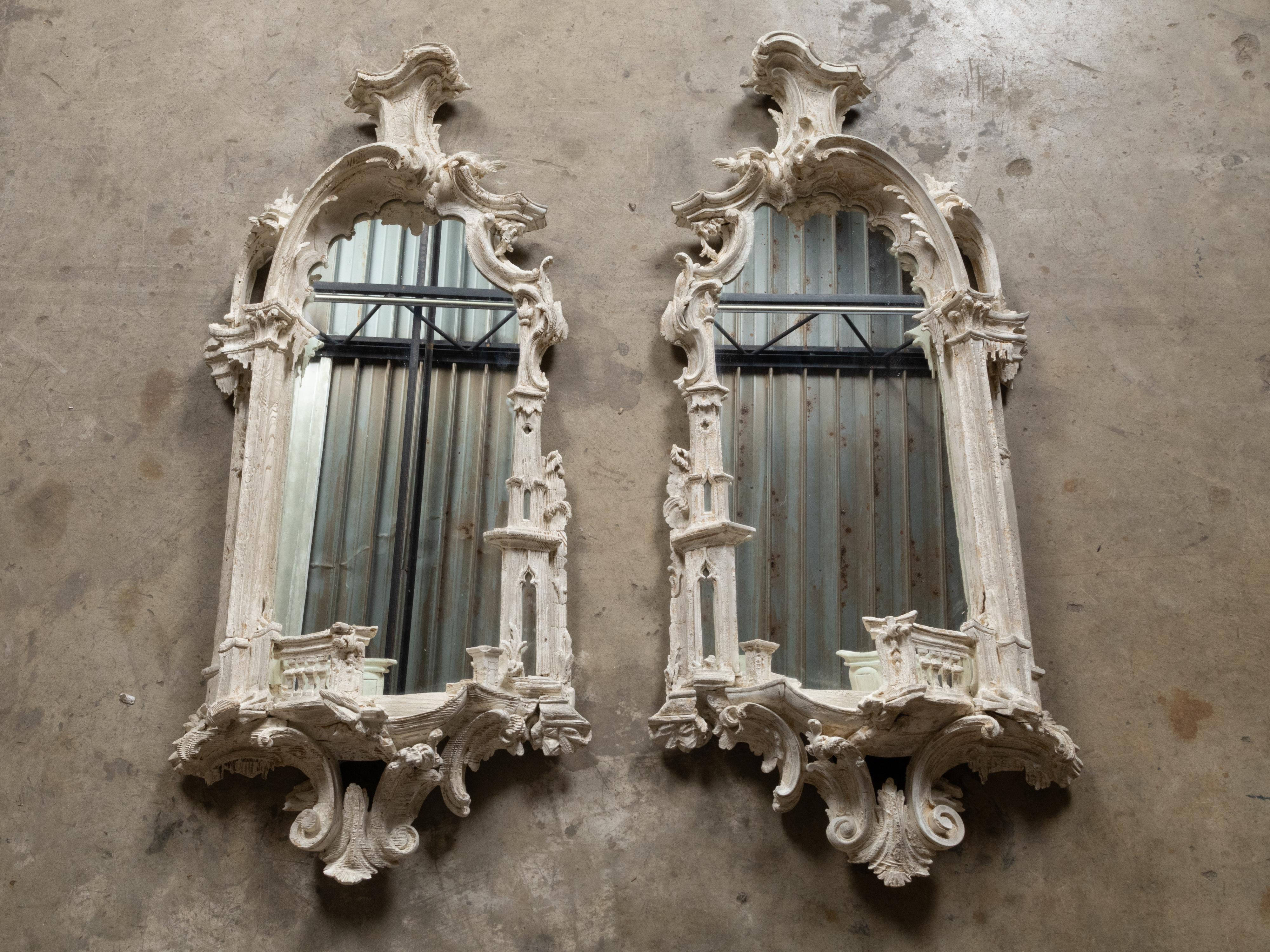 A pair of English Rococo Chippendale style carved and painted mirror from the 19th century with richly carved frames. This exquisite pair of English Rococo Chippendale style mirrors from the 19th century features richly carved frames that epitomize