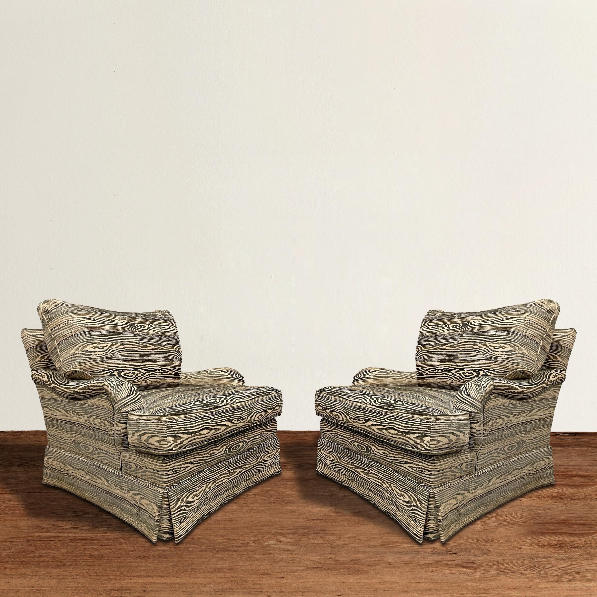 A spirited and spunky pair of 20th century English roll arm chairs upholstered in a bold chenille with raised faux-bois wood grain pattern. Down-filled back and seat cushions, skirted bases, and a down-filled throw pillow included with each chair.