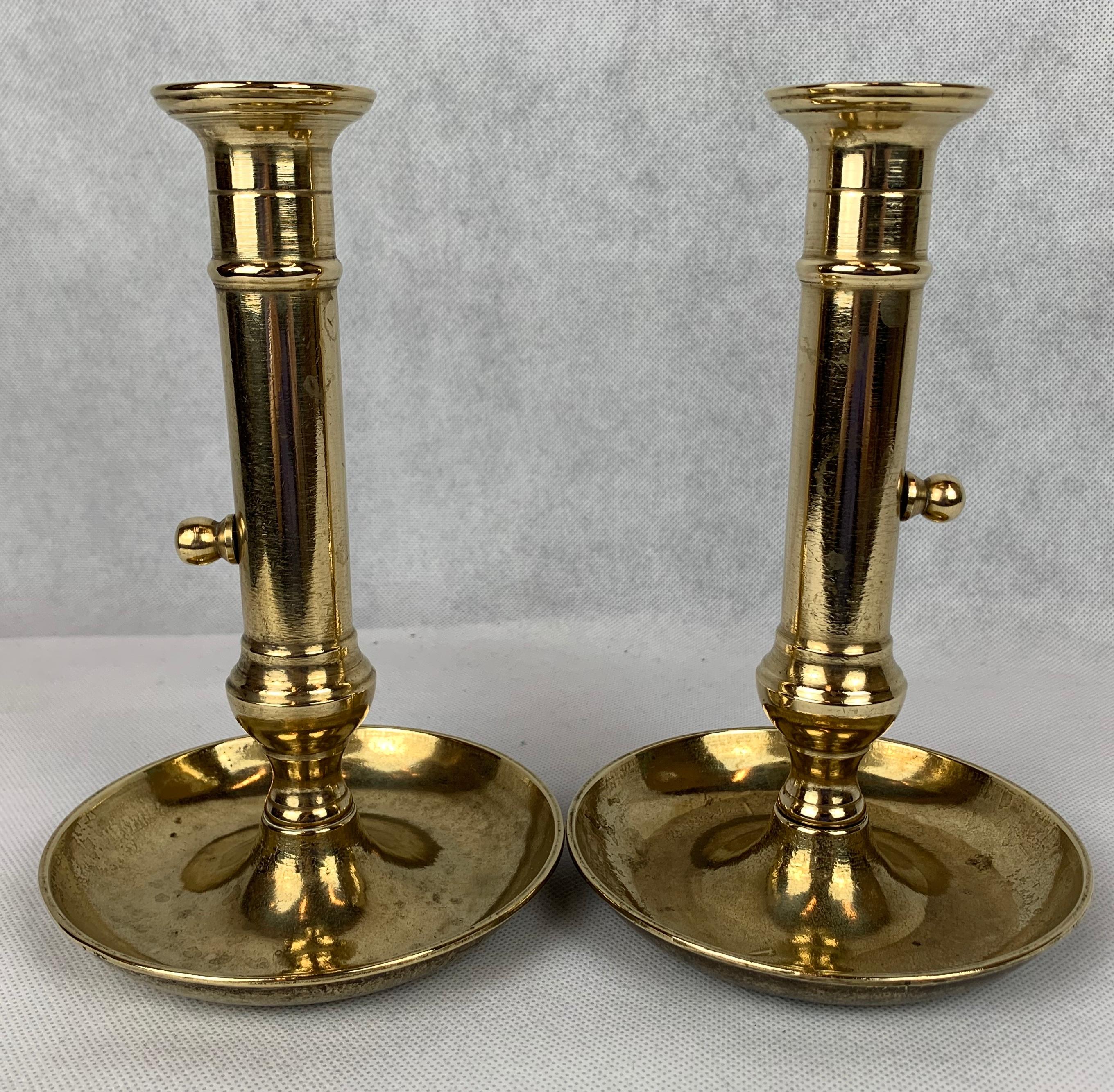 A pair of late 18th century solid brass side ejector chambersticks. The saucer base usually indicates they were used as 