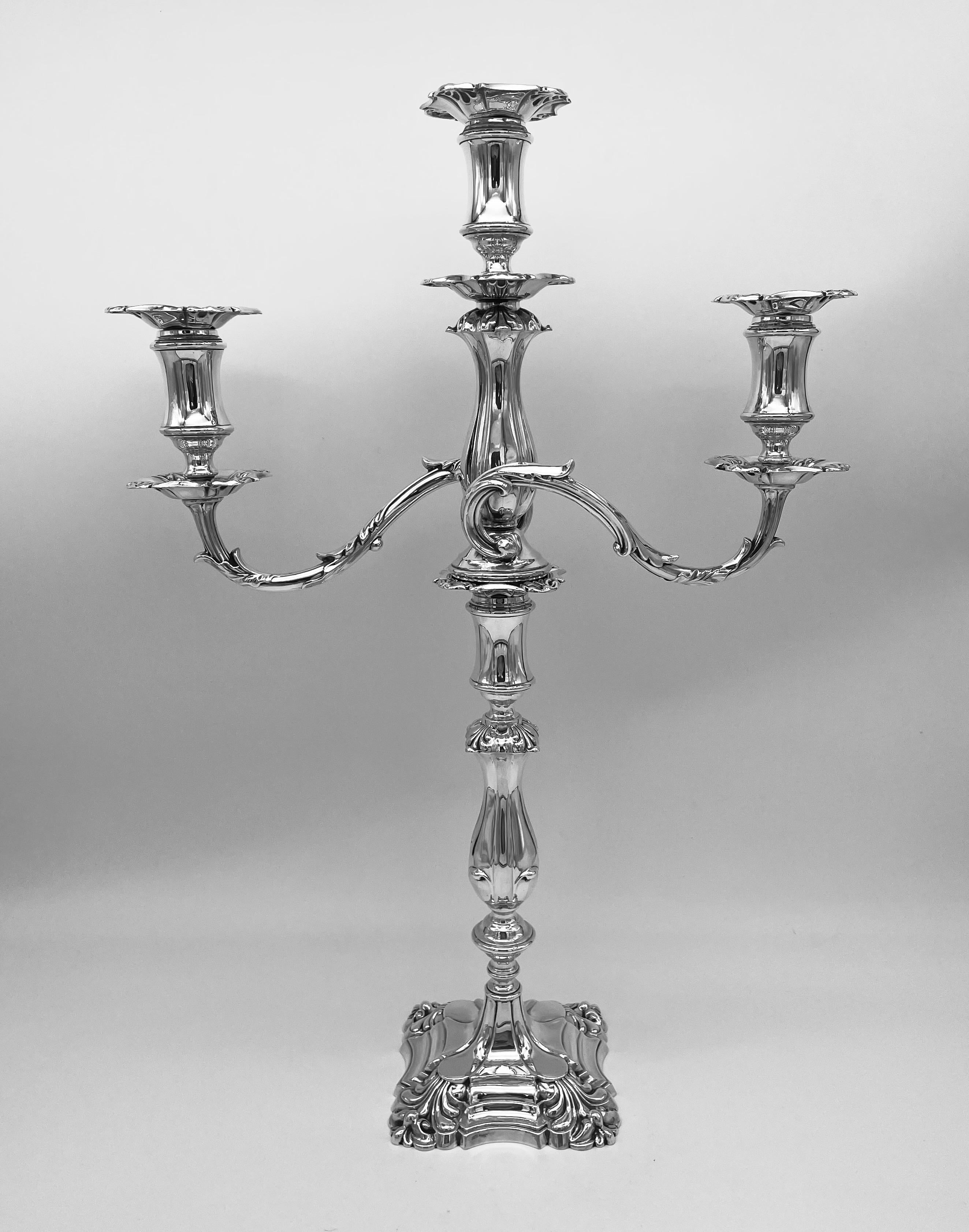 A large and impactful pair of George V sterling silver three light candelabra, Sheffield 1928 by Walker and Hall

The filled candlestick bases of shaped and incurved square form with splayed shell scroll corners, the central column with circular