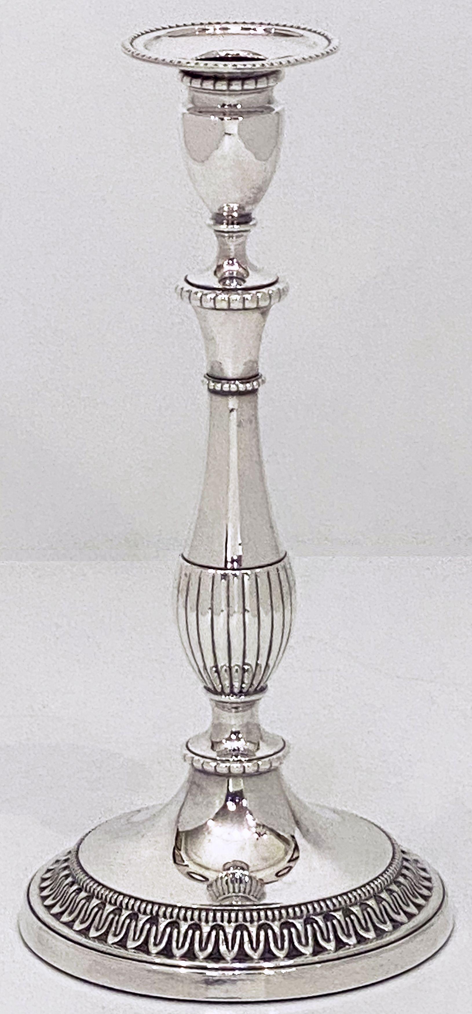 A handsome pair of English candlestick holders of fine plate silver featuring a relief with a neo-classical design.