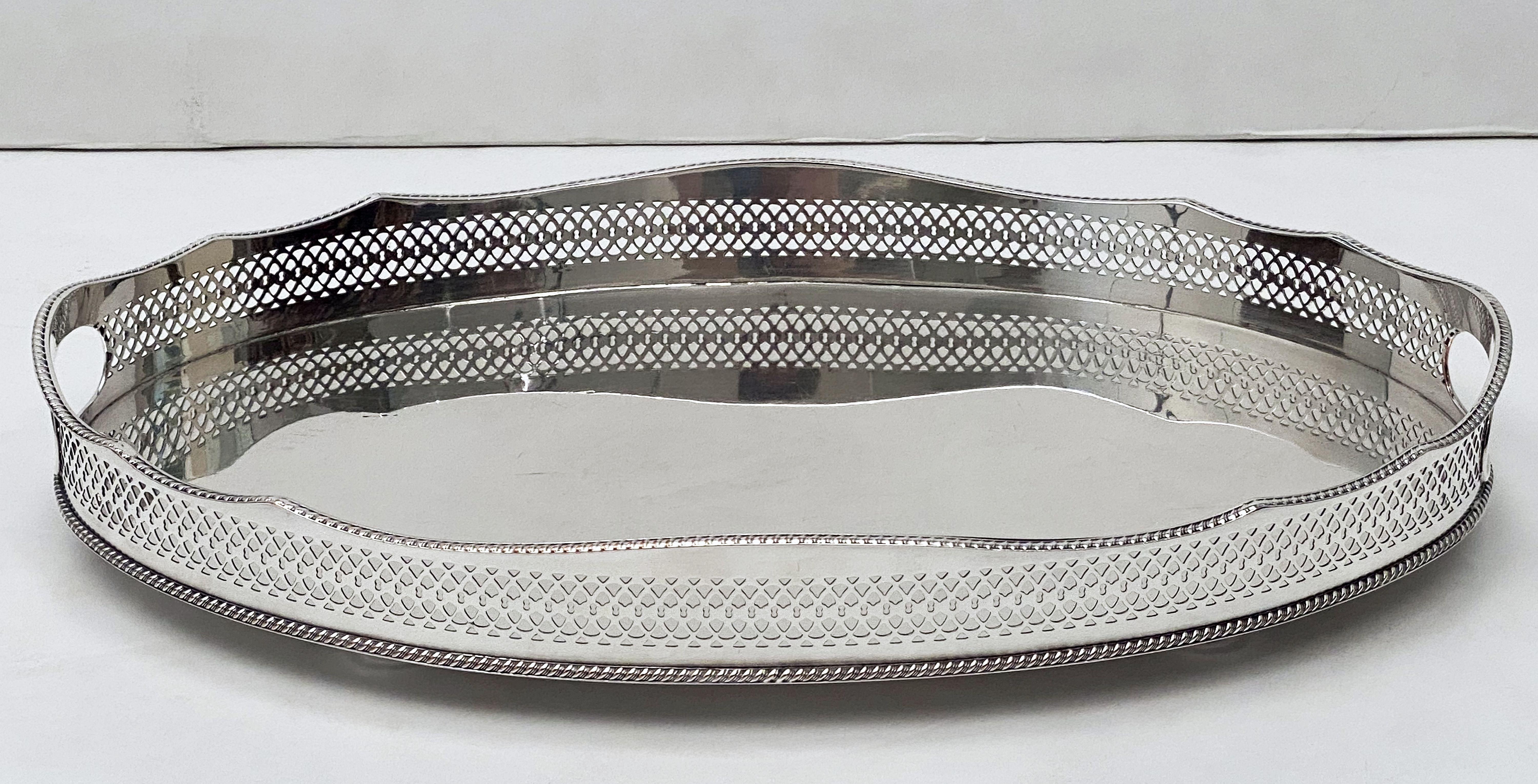 A handsome pair of large English oval gallery serving or drinks trays (or platters), each with pierced serpentine gallery around the circumference.
of fine English plate silver. 

Dimensions: Gallery H 2 3/4 inches x W 18 1/4 inches x D 12 1/4