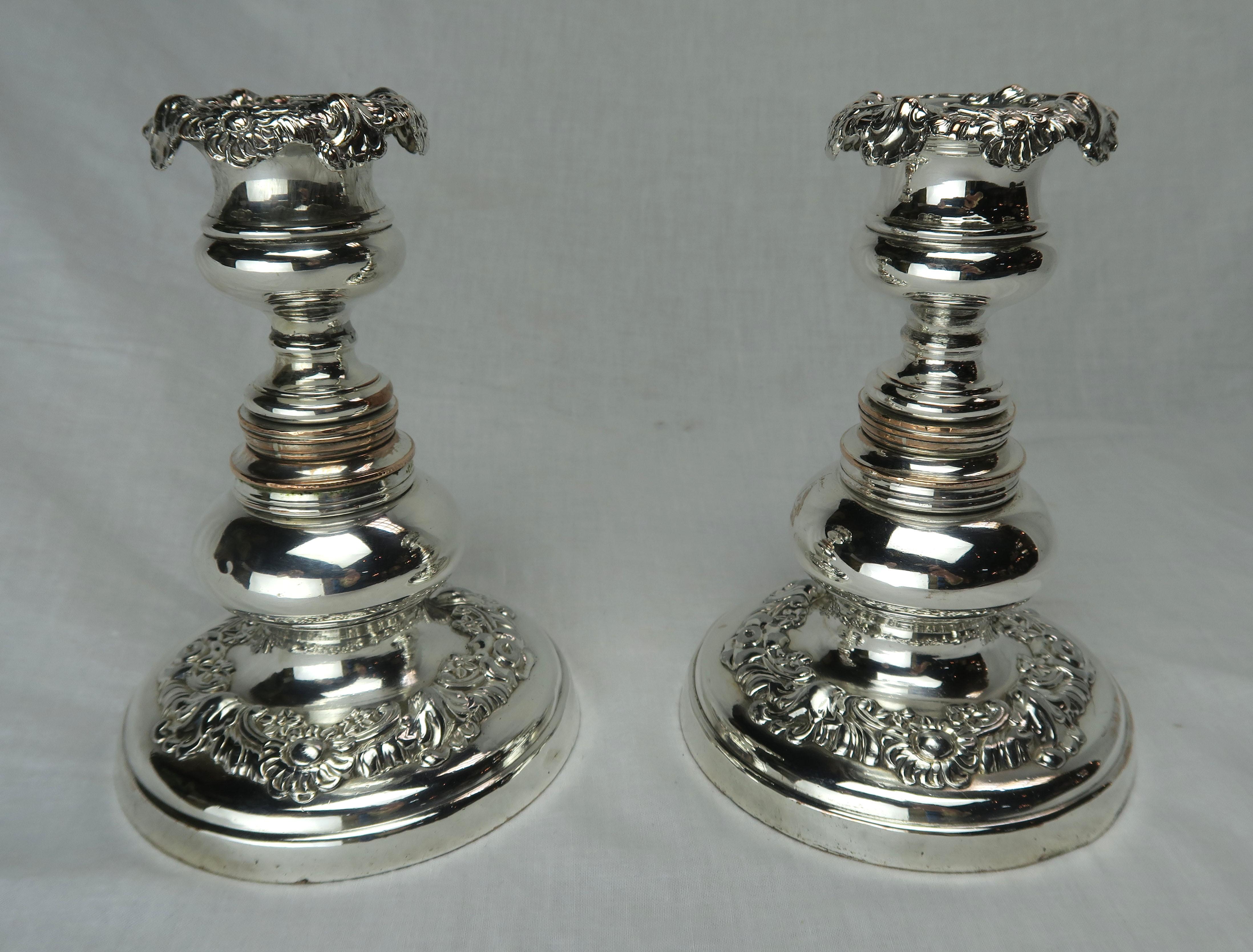 Pair of English silver repoussee candlesticks with floral design throughout. Heavy silver over copper plated. No makers mark.