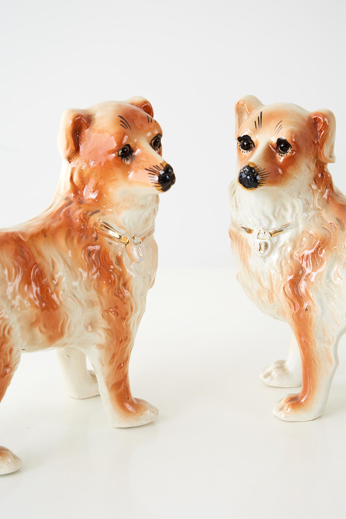 Lovely pair of English Staffordshire dogs depicted standing. Decorated with beautiful wavy fur and delicate faces. Each has a gilt collar and a rich orangish glaze. The bottoms have a faint craquelure detail in the finish.