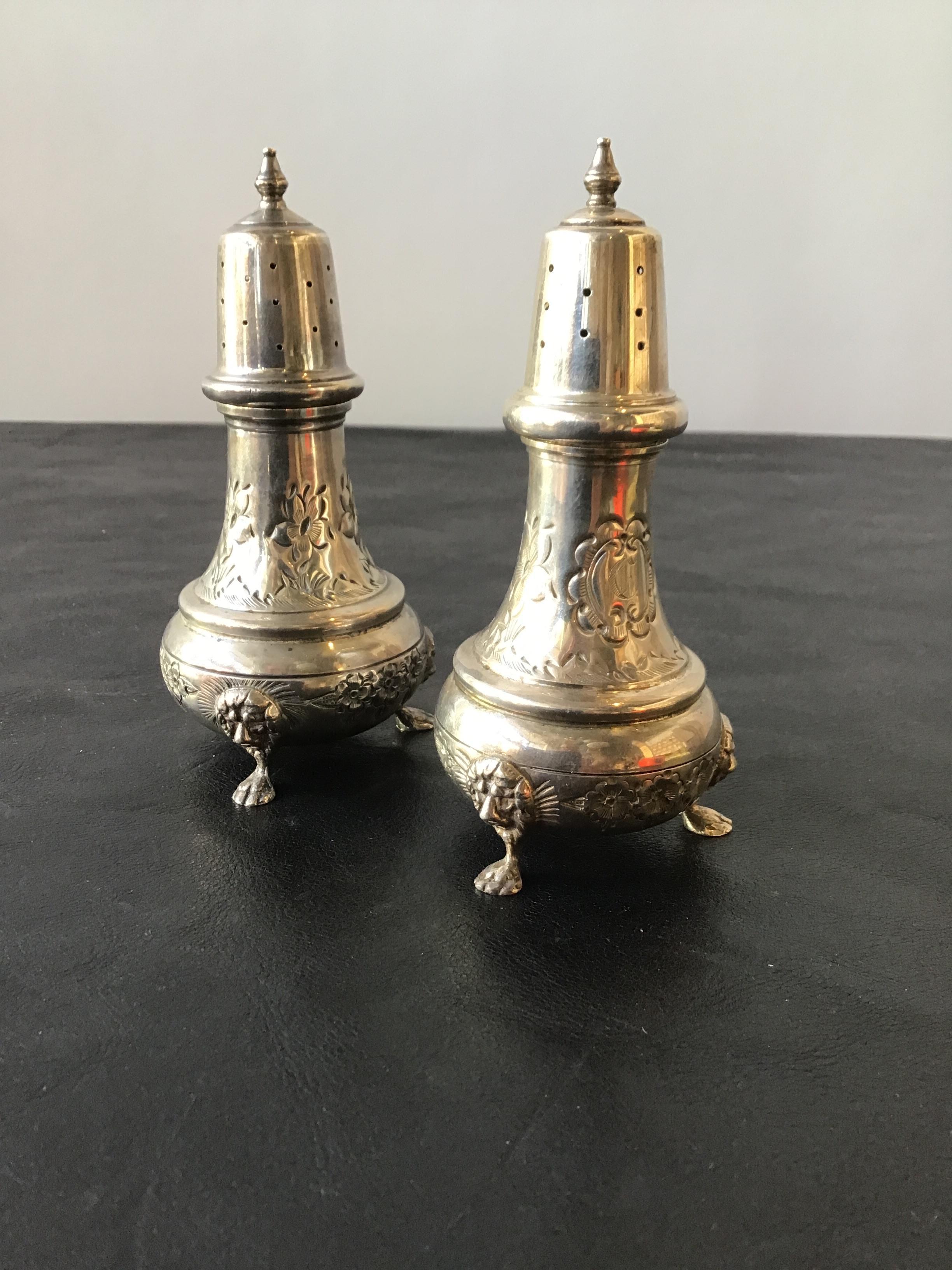 Pair of turn of the century, English solid sterling hand chase salt and pepper shakers with lion foot. Weighs 5.5 ounces. Initials inscribed on shakers.