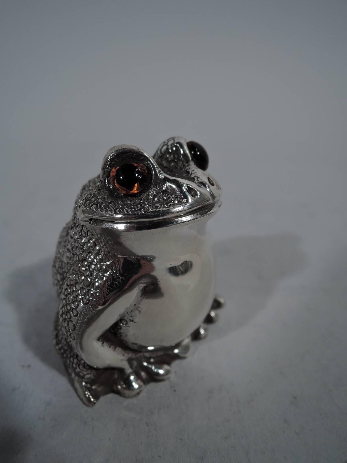 Pair of English sterling silver figural salt and pepper shakers. Each: A squatting reptile with legs gathered close to body. Scaly back, smooth front, and intense glass exophthalmic eyes. Closed mouth set in smirking smile. Plastic plug. London