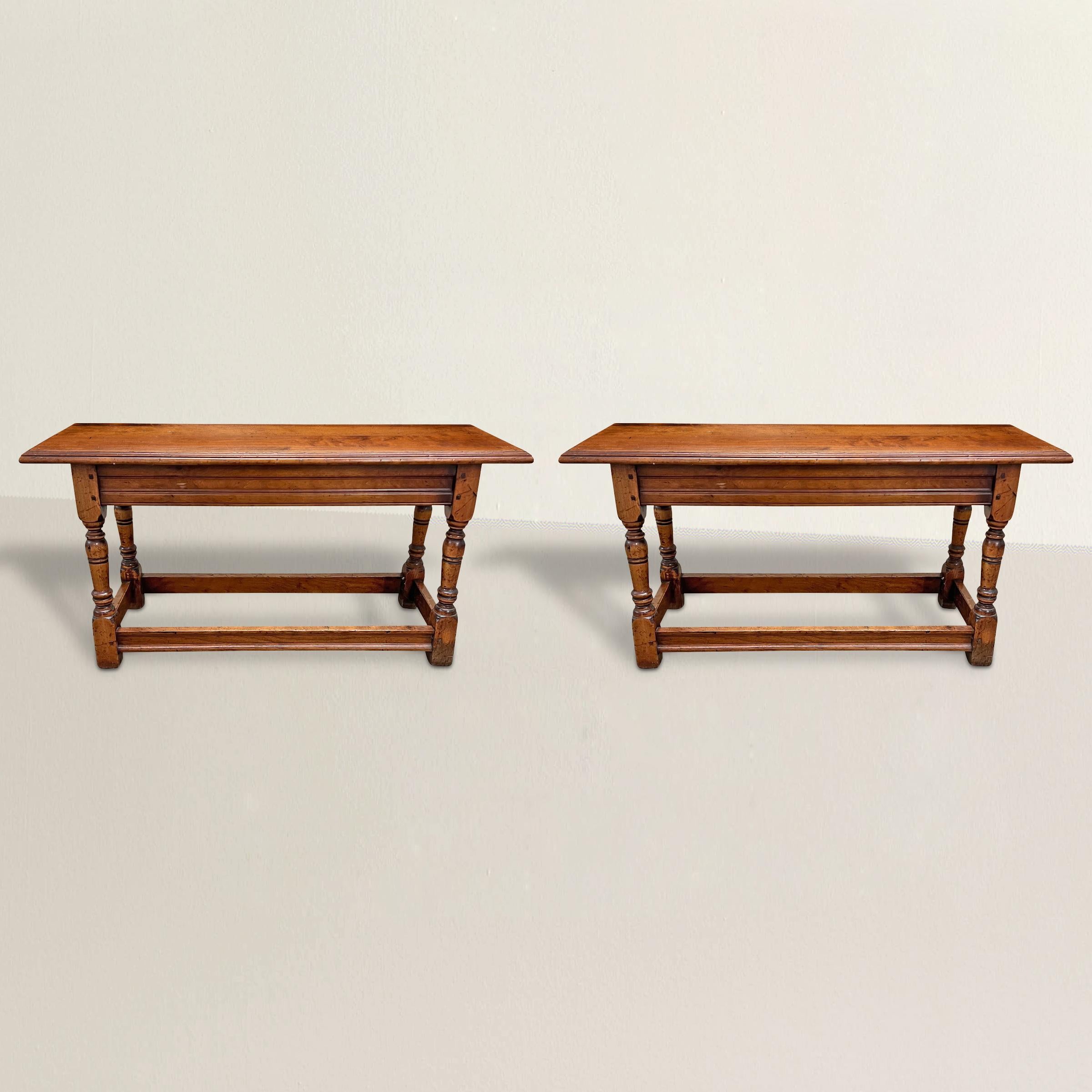 A charming pair of late 20th century English elmwood benches with turned tapered legs with simple pegged stretchers. Perfect on either side of your breakfast table, at the foot of twin beds, or running down the hall of your country house.
