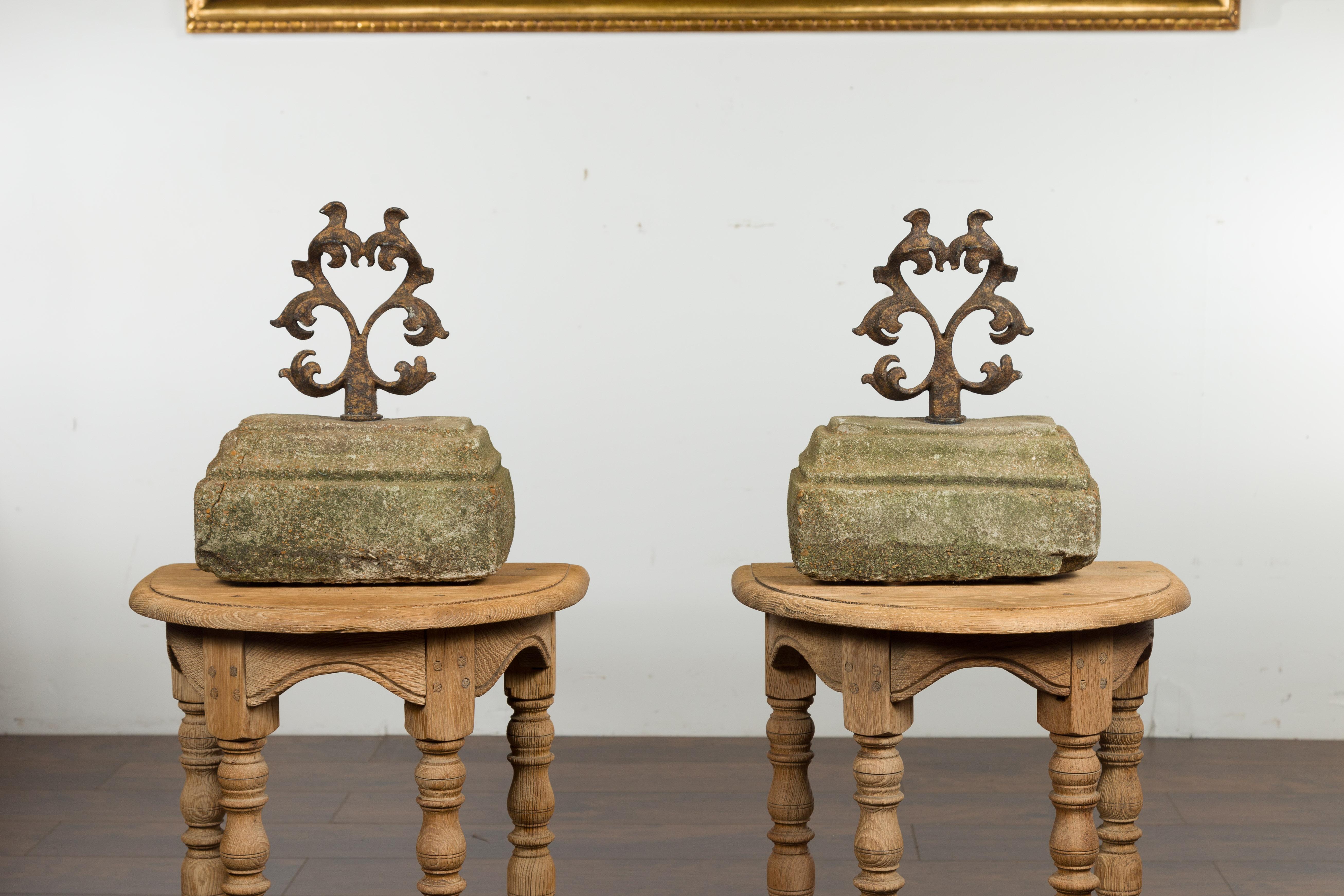 A pair of English iron and stone door stops/boot scrappers from the early 20th century, with scrolling motifs. Created in England at the turn of the century, each of this pair of stone door stops/boot scrappers is topped with double scrolling iron