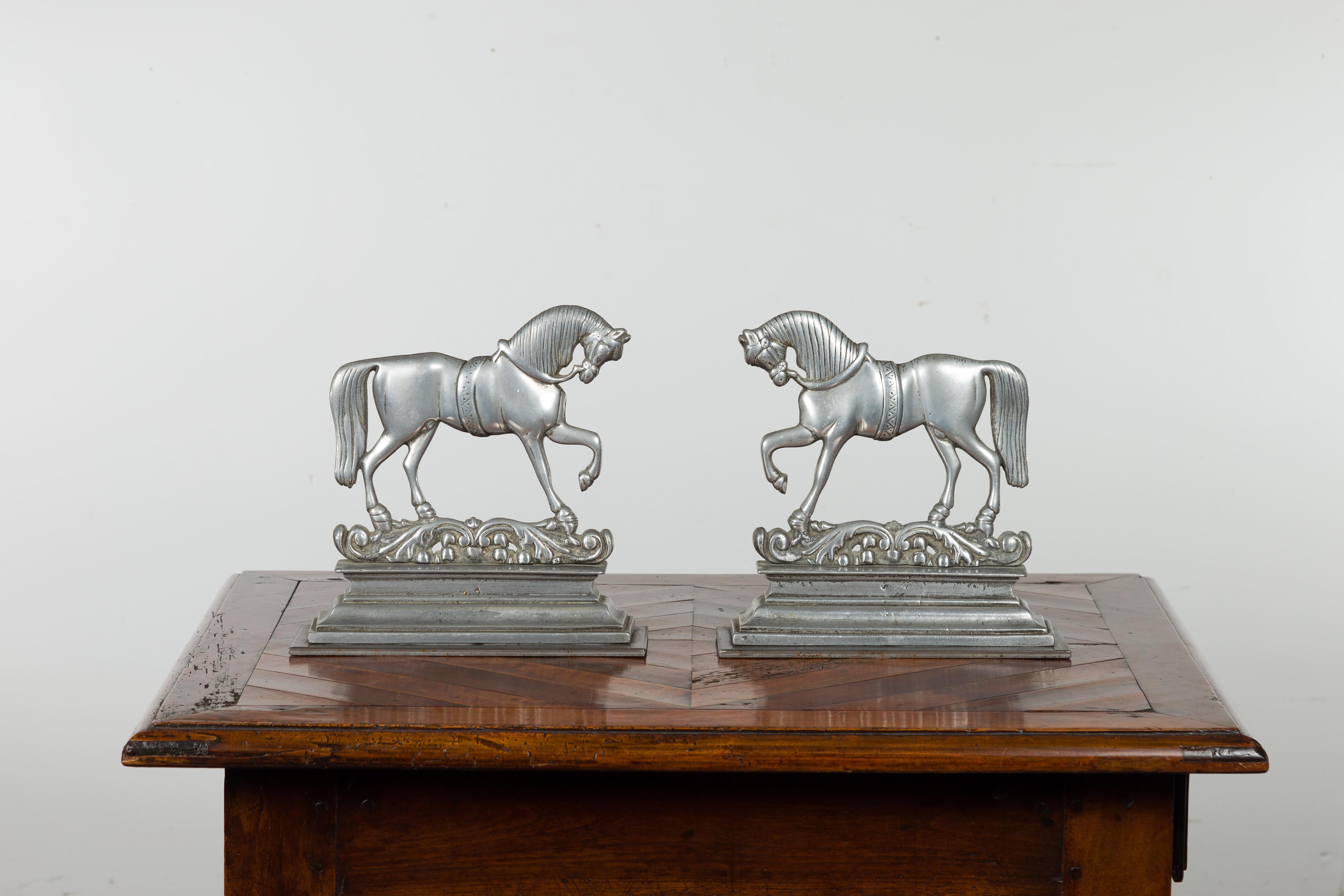 A pair of English silver toned metal prancing horses from the early 20th century, perfect to be used as bookends. Created in England during the turn of the century, each of this pair of metal bookends features elegant horses standing gracefully on a
