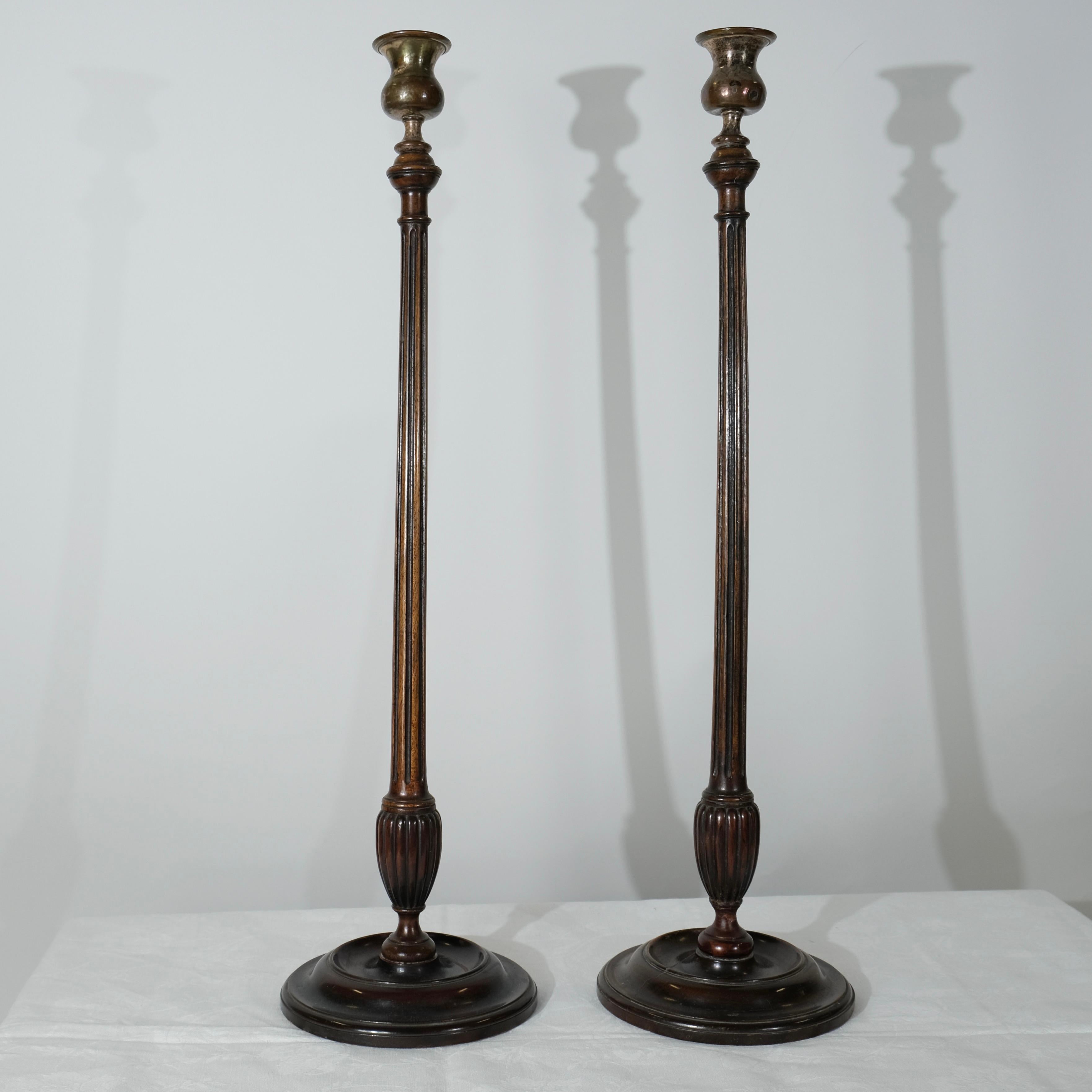 Ces élégants chandeliers, d'une hauteur impressionnante de 59 cm, présentent une silhouette raffinée et allongée qui dégage une impression de sophistication classique. Les tiges fines et cannelées sont minutieusement travaillées, mettant en valeur