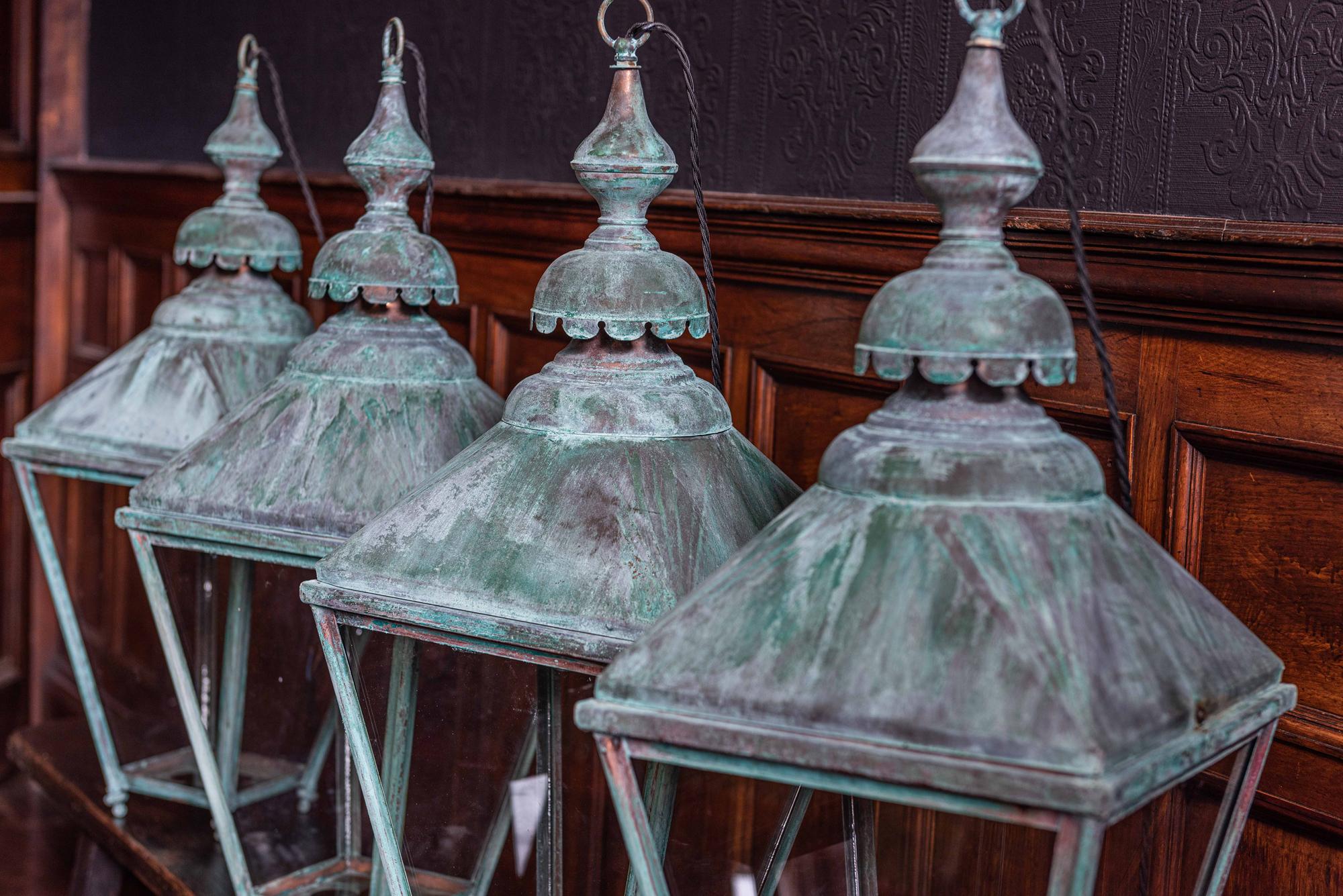 Pair of English verdigris copper lanterns,
circa 1940.

With screw fit canopies for bulb removal and interesting quarter foil cut shapes to the bases

They come with 1m of silk flex, 1m of heavy gauge antique brass chain and bronze ceiling