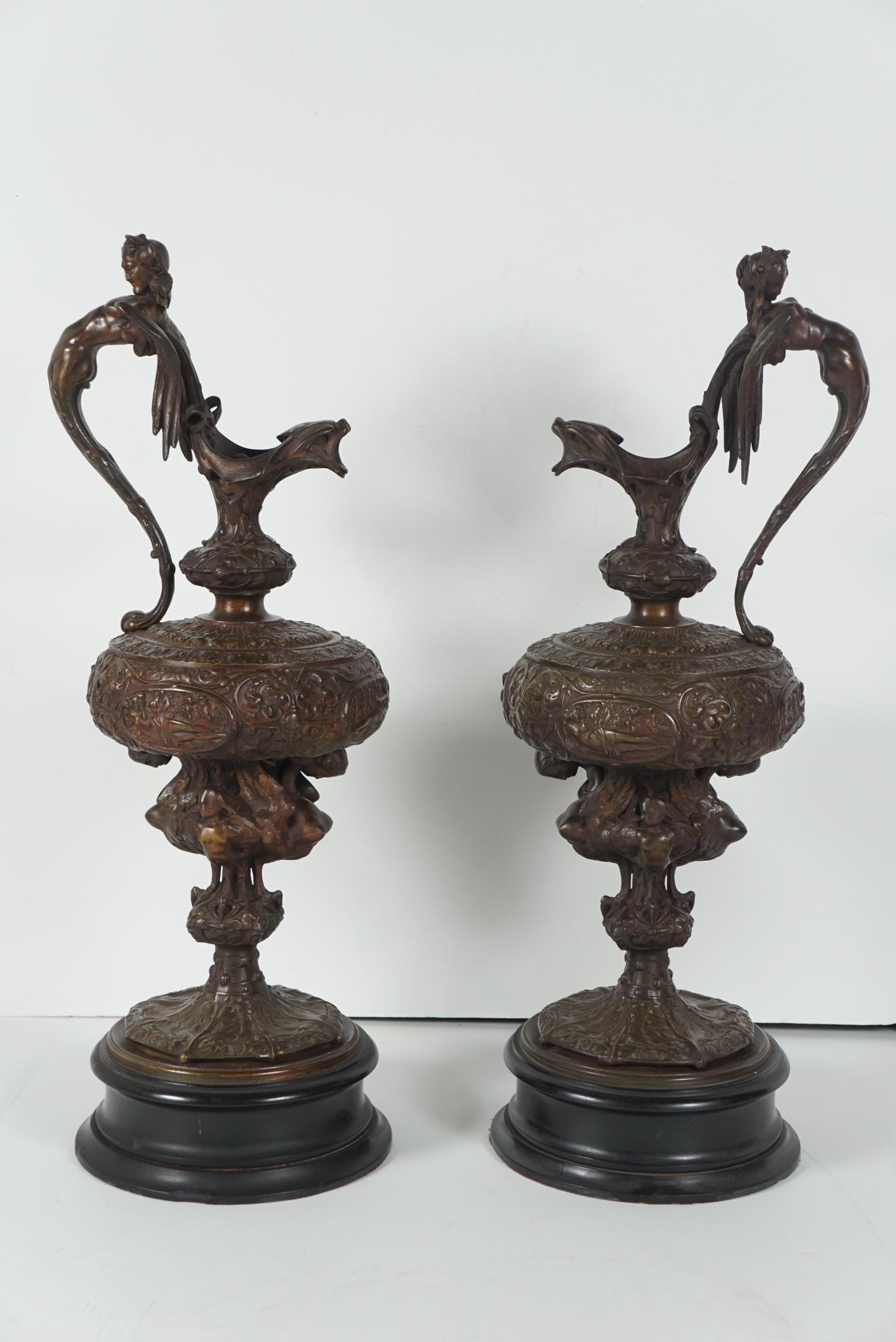 These large and very detailed Renaissance Revival cast bronze decorative ewers come from England and were made circa 1870. The body of the vases are divided into oval plaques representing allegorical scenes from the past all surrounded by arabesques