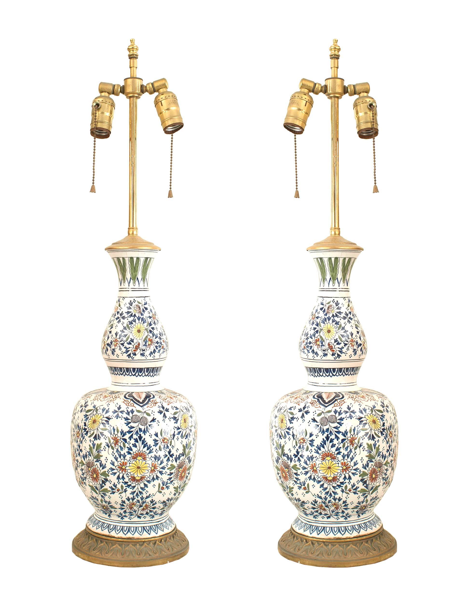 Pair of English Victorian (19th-20th century) round two-tiered white porcelain lamps with red and blue floral decoration resting on a gilt metal base.
  