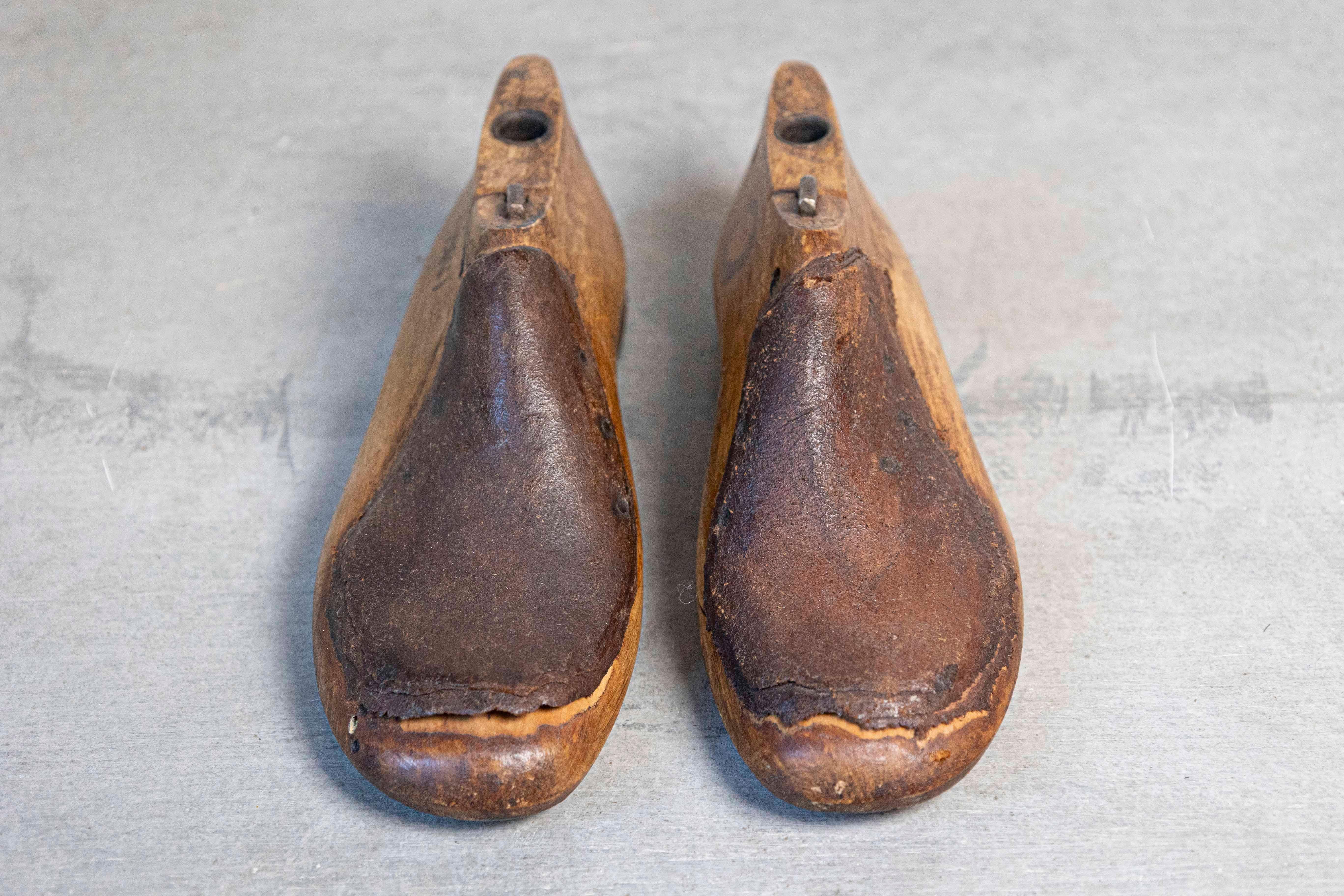 A vintage pair of English wood and leather cobbler's shoe lasts from the 20th century, numbered on the side. Handmade out of wood and used to create shoes for certain clients, this pair of shoe lasts is numbered on the side. Presenting a nicely