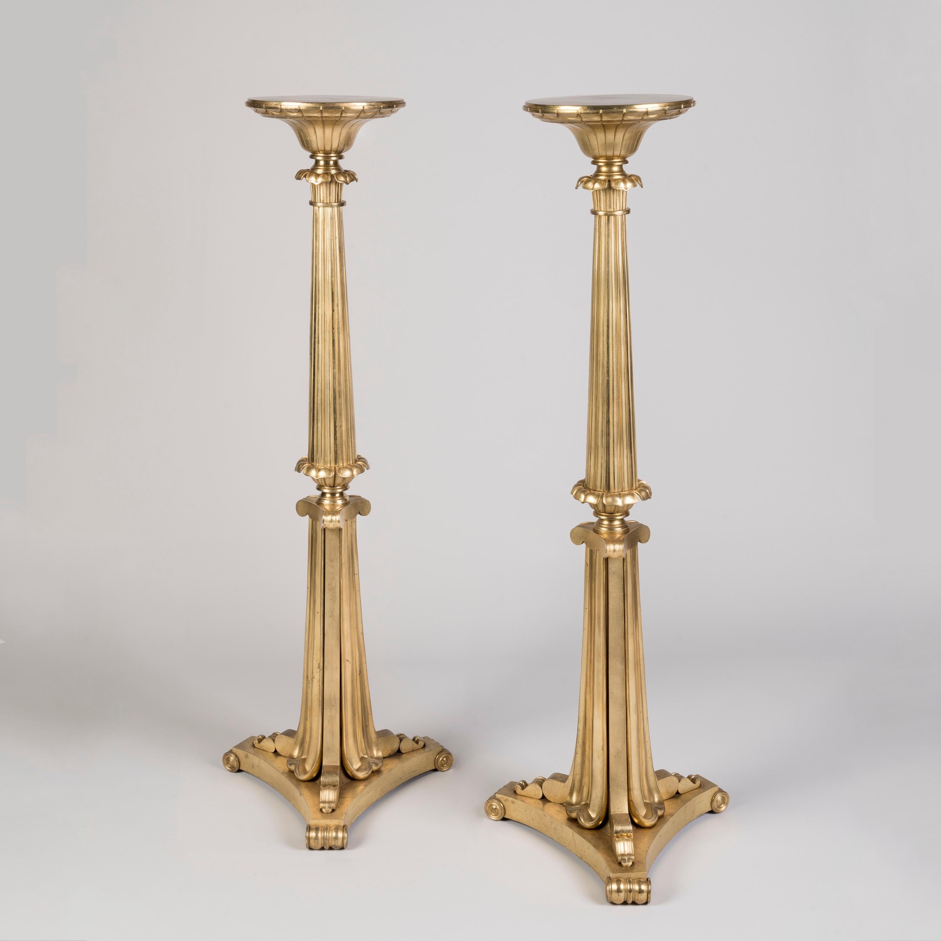 A Pair of William IV Gilt Bronze Torchères

Each of the tall stands with circular tops and engraved swags to the bowl, emerging from the lotus-leaf cast, tapering and reeded stem joined to the three-sided lower half consisting of a concave base with