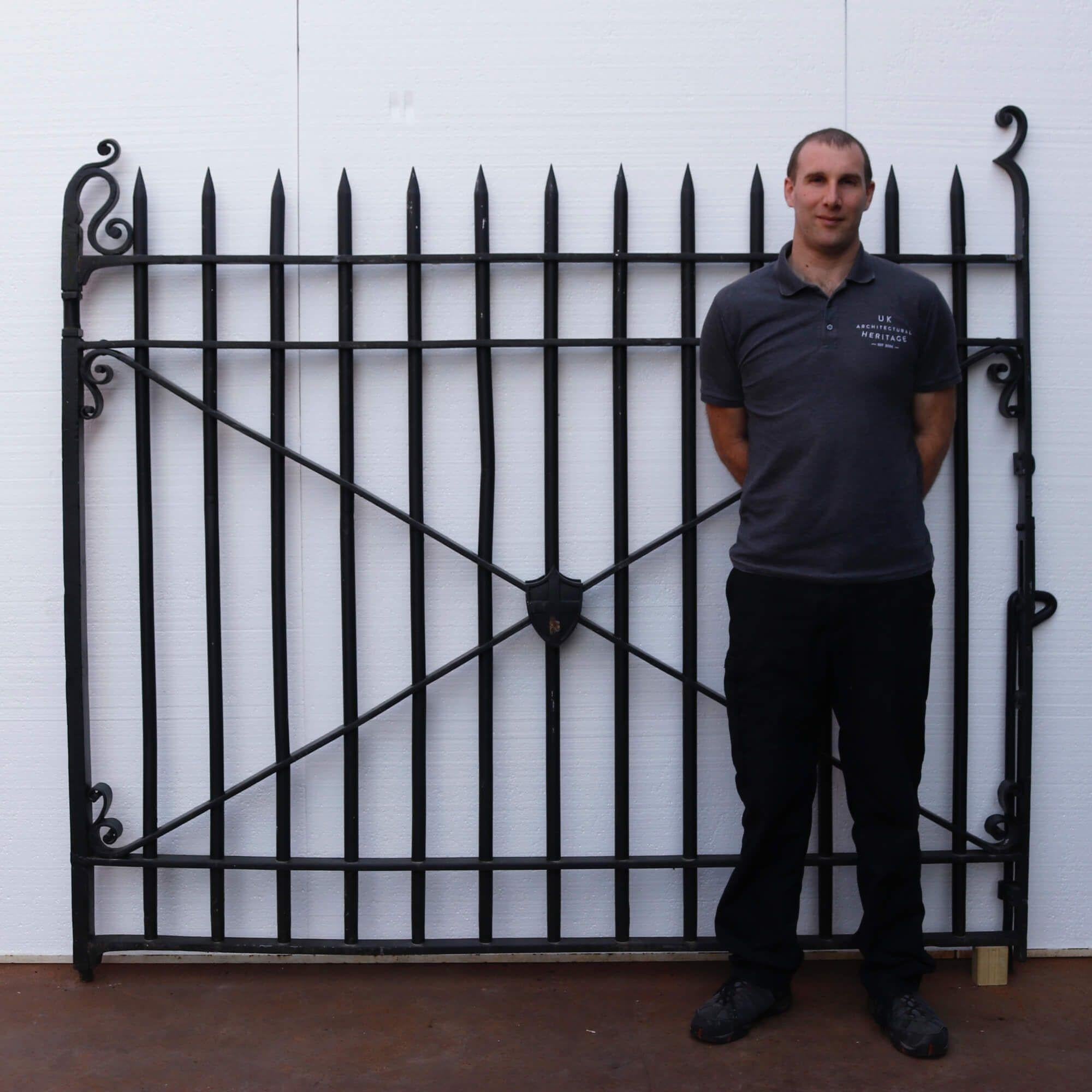 Pair of antique 20th century English wrought iron driveway gates. These substantially constructed blacksmith made gates have a significant decorative shield of St George’s cross, which appears on England’s flag. There is also a pedestrian gate at