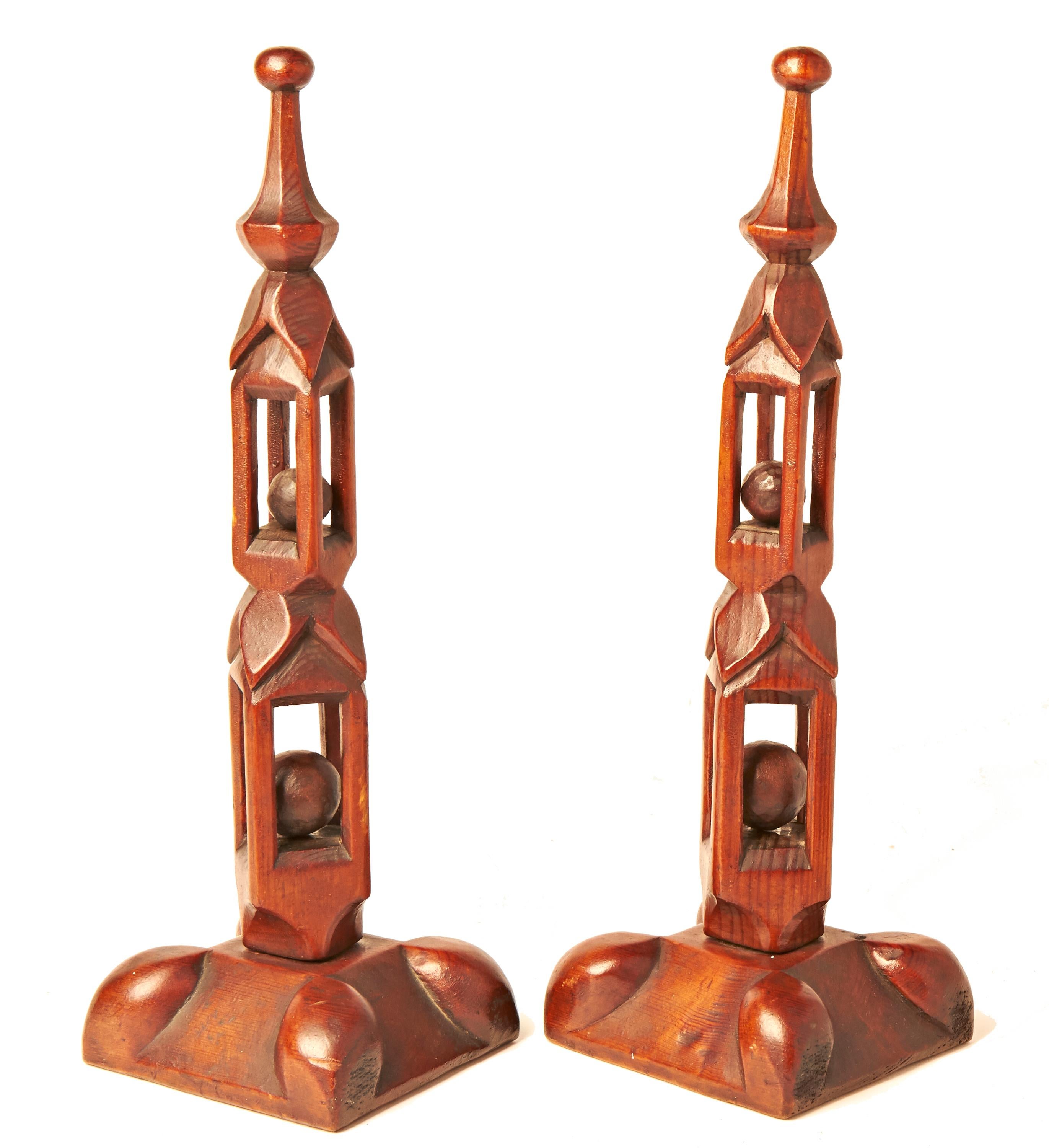 This pair of Trench art hand carved Treen puzzle obelisks each feature a lopped pyramid square plinth with ovoid shaped cushions at each corner. The obelisks themselves are each constructed from a single column of wood that is segmented by two