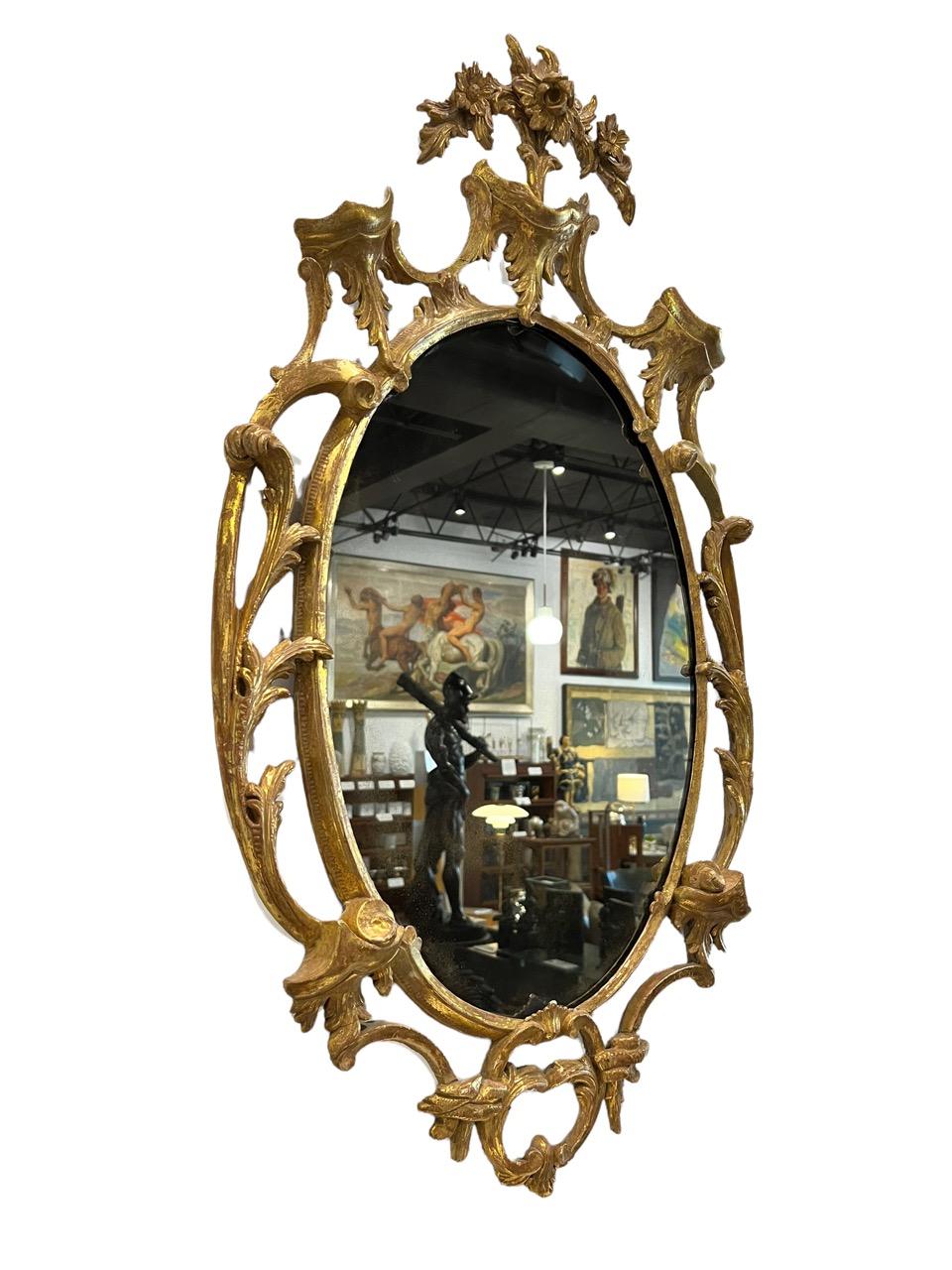 Pair of English 18th century (circa 1765) rococo (Chippendale) gilt mirrors oval shaped framed with elaborate hand-carved frames with c scrolls, acanthus and foliage.
 