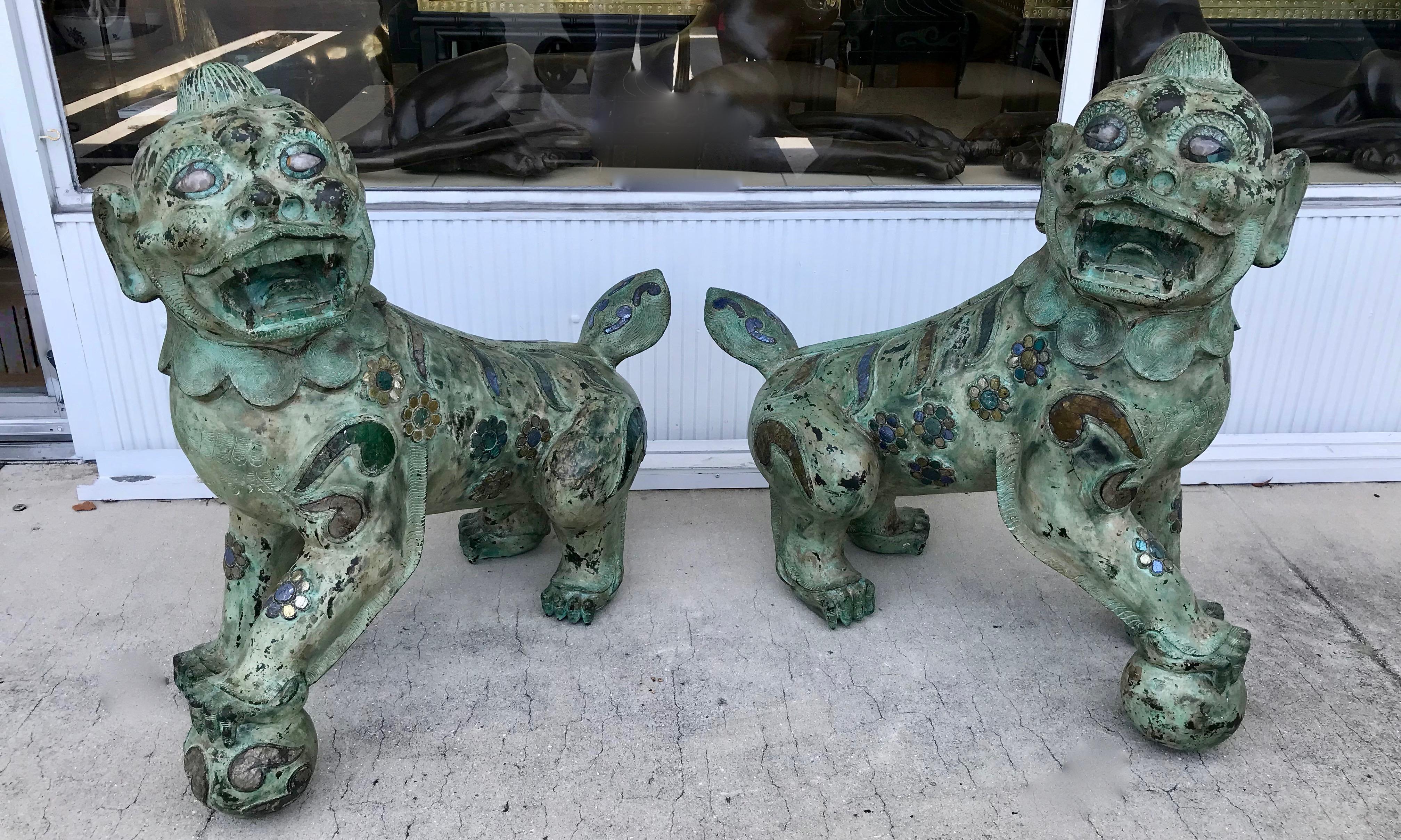 The impressively scaled foo dogs are a proper pair - one posed left , 
the other right. Both are fashioned with quartz eyes and mica and other
inlays. The patinated figures are embossed with engravings in their
manes. These are a rare and stellar