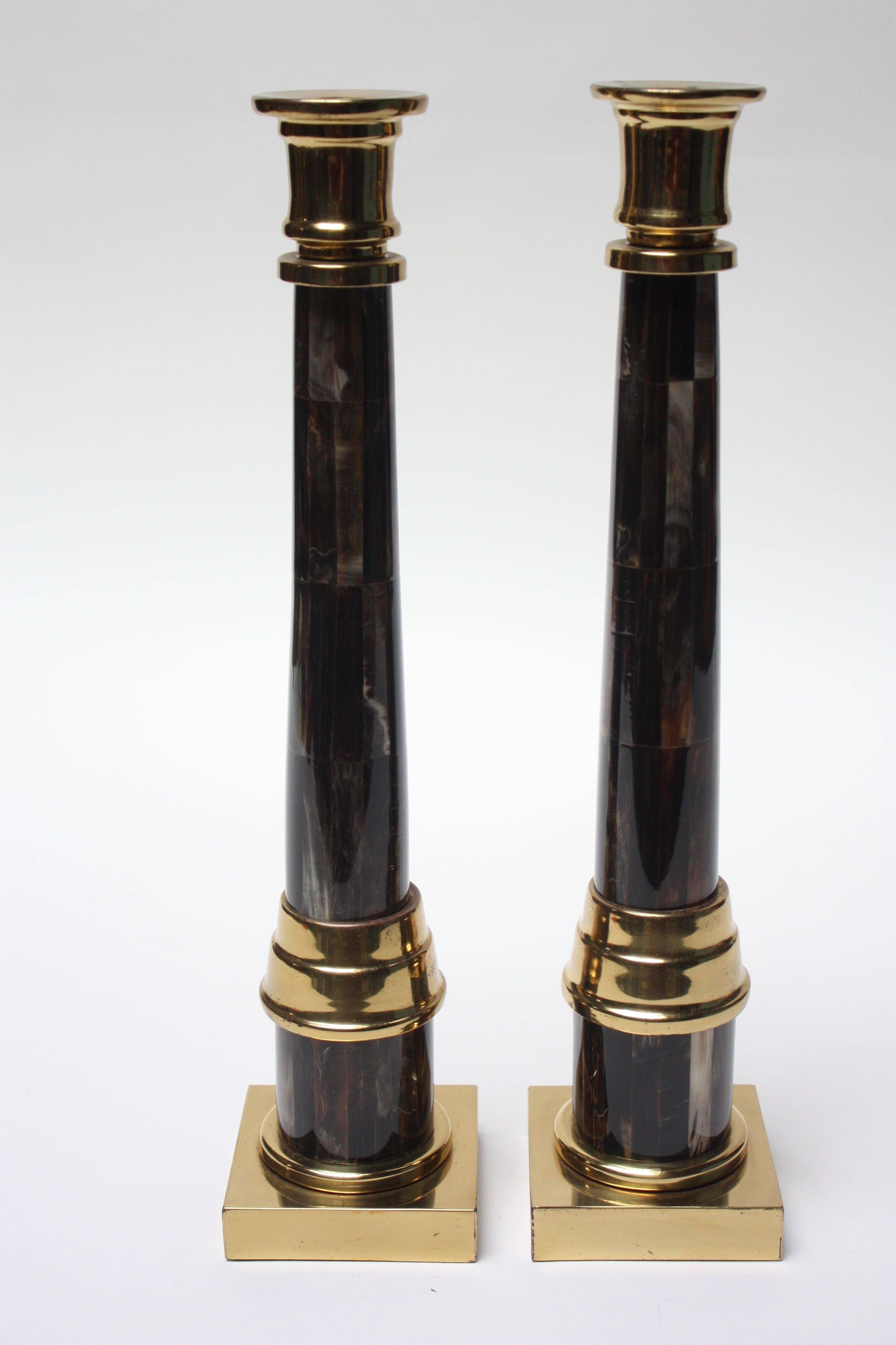 Glamorous pair of Hollywood Regency style candlesticks made by Enrique Garcel (Colombia, circa late 1970s-early 1980s). They are composed of organic material wrapped in a glass like resin with solid brass accents. Given the handmade nature of these