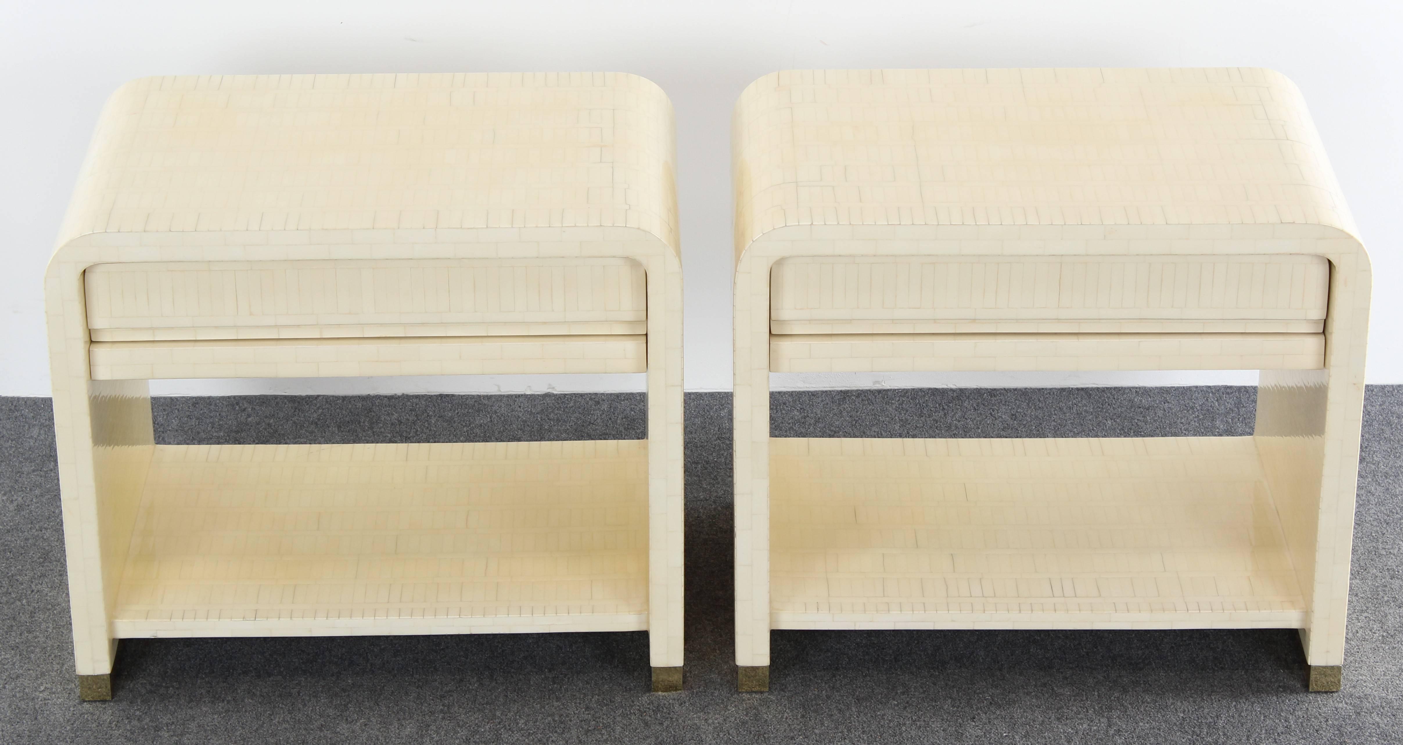 A pair of exquisite Enrique Garcel tessellated bone bedside or end tables with brass platform base. These were purchased in 1988 with original bill of receipt for $7,500. Good condition with age appropriate wear.