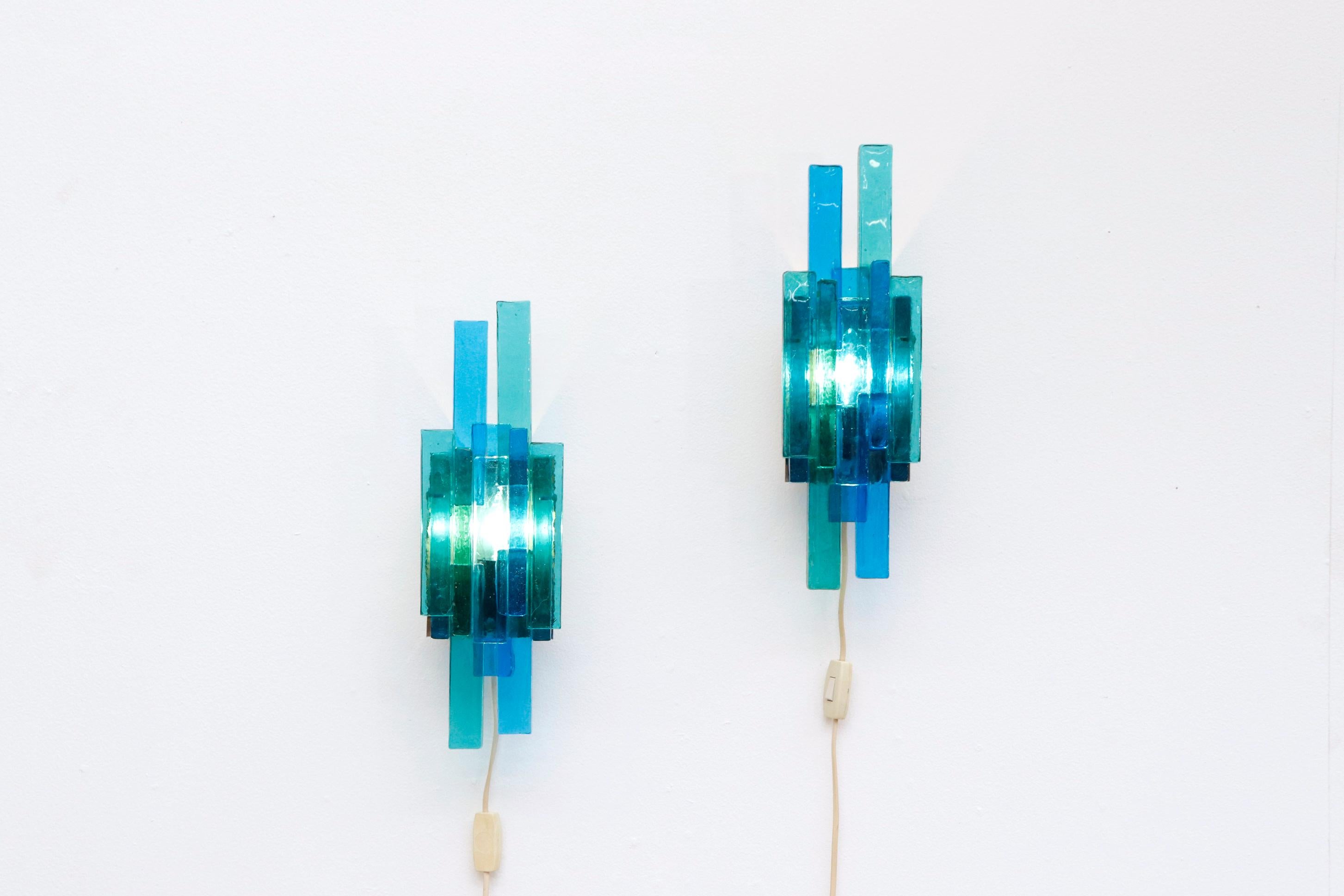 Beautiful pair of Eric Hoglund style wall sconces with heavy blue and green glass and enameled metal mounts. In original condition with original European sockets, US plug added. Wear consistent with age and use. Set price.