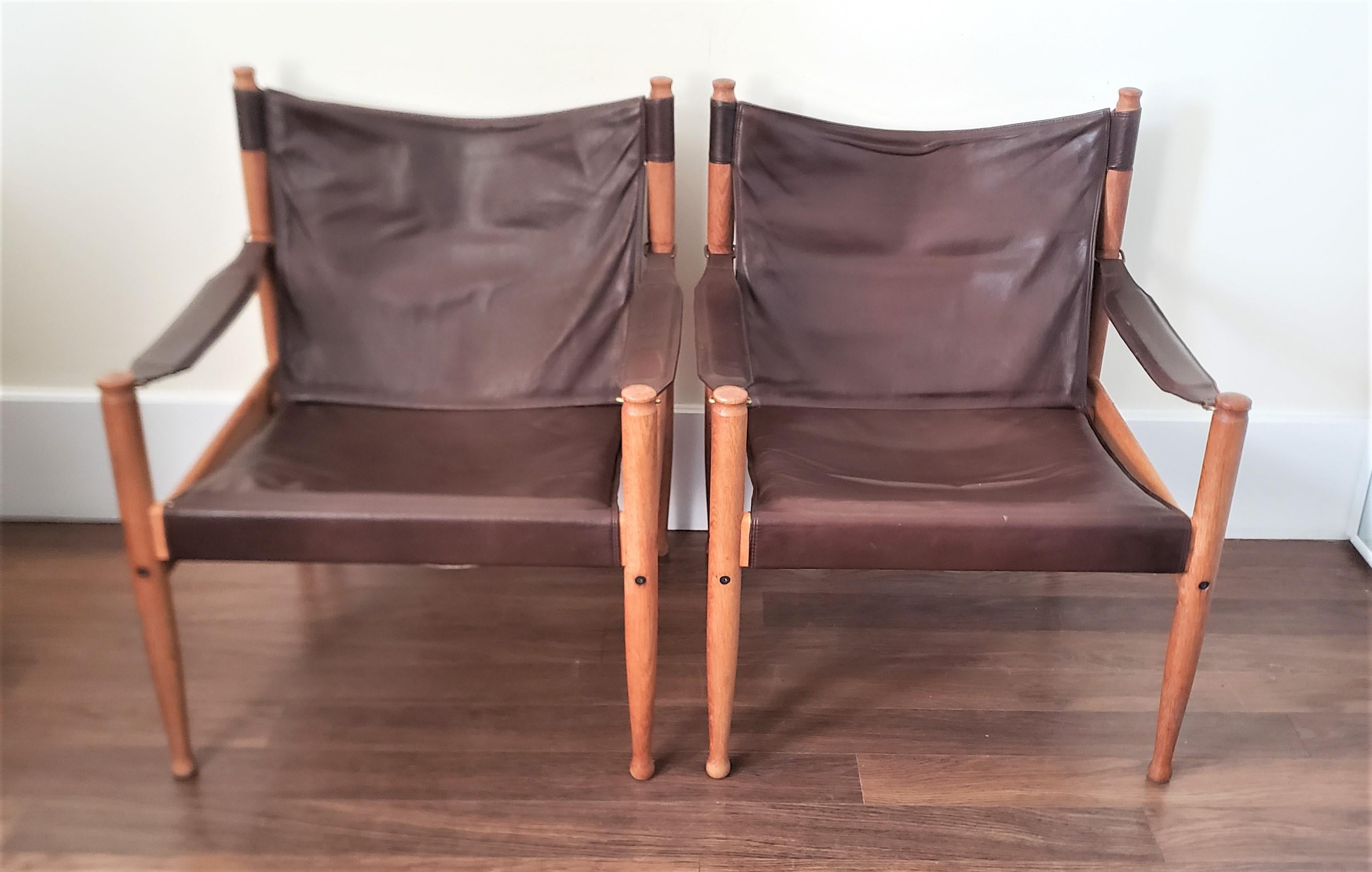 This pair of lounge chairs were designed by Erik Worts and made by Niels Eilersen of Denmark in approximately 1960 in the period Mid-Century Modern style. The frames of the chairs are done in teak with dark brown leather and brass accents. Both