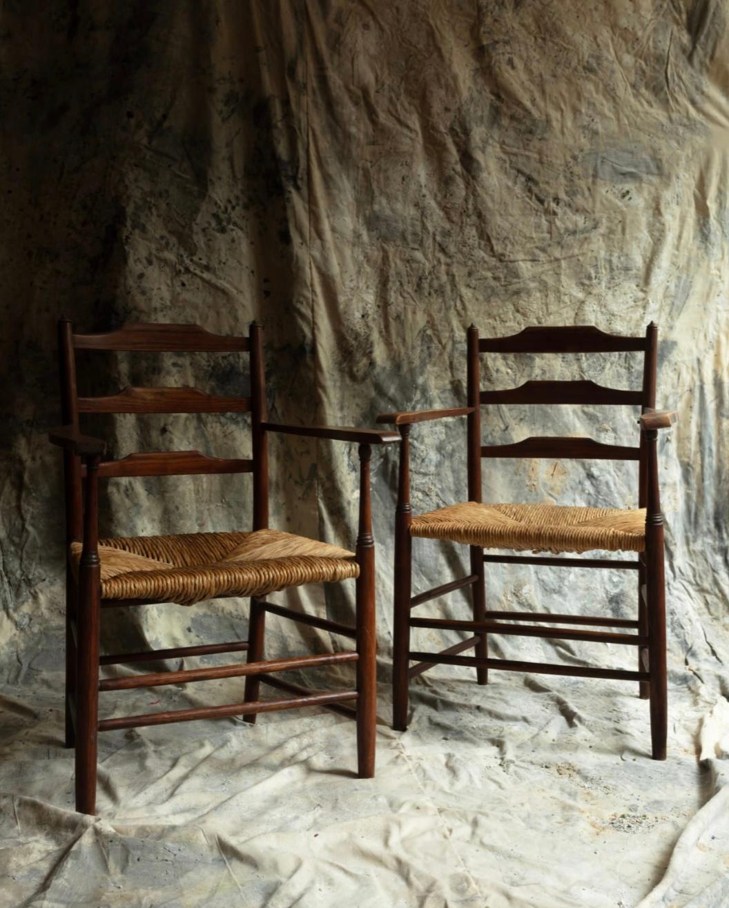 Coppia di poltrone basse con schienale a scaletta di Ernest Gimson in frassino con sedute in giunco realizzate dal suo sediaio Edward Gardiner nel 1920 circa. Il design e l'interazione tra Gimson, James Maclaren e Philip Clissett, che insegnò a