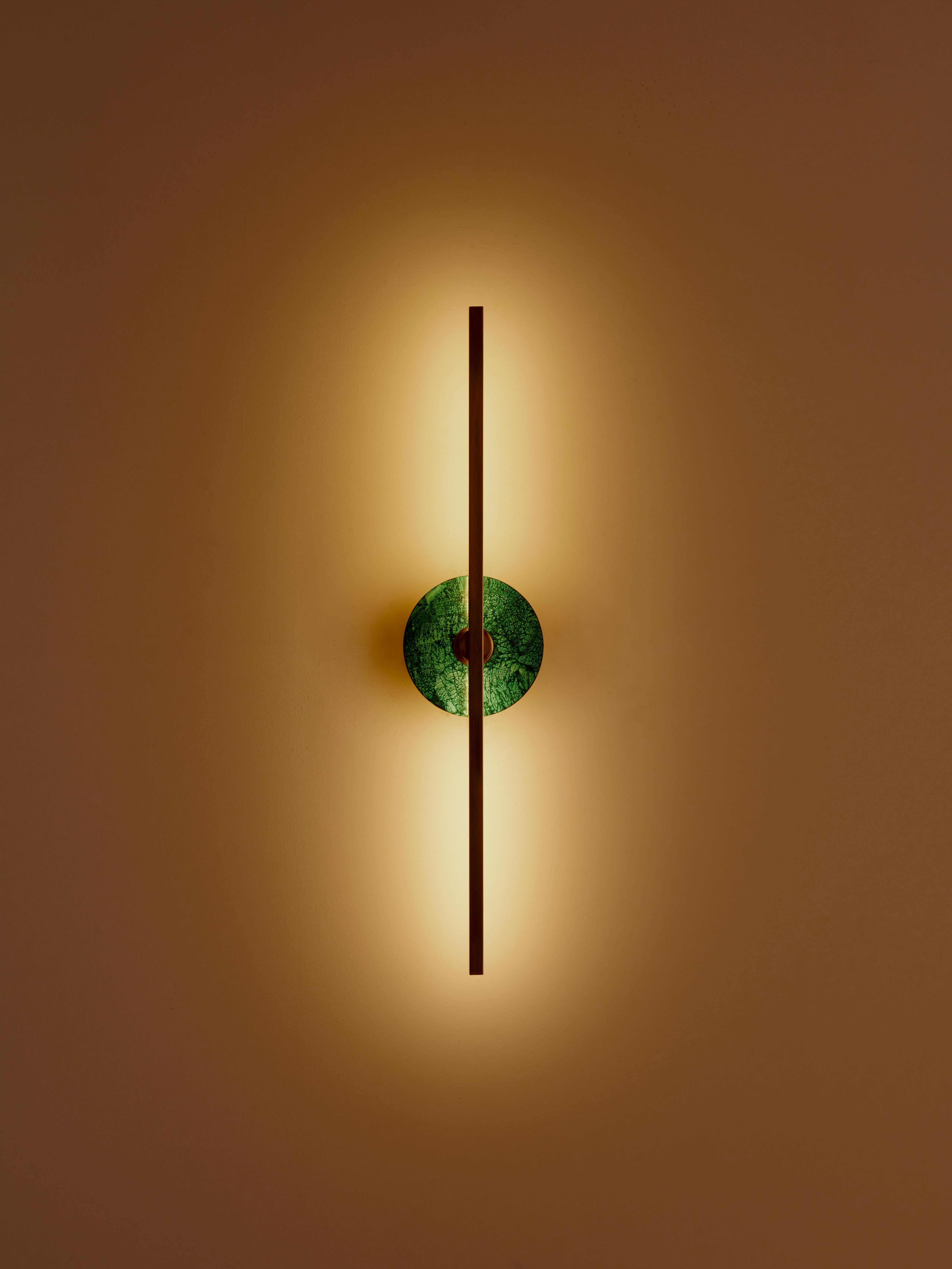 The Elite Stick wall sconce combines the minimalism of thin brass profiles with the functionality and power of led technology, offering a warm and diffused light. The malachite, pure decorative element, embellishes the structure of the product with