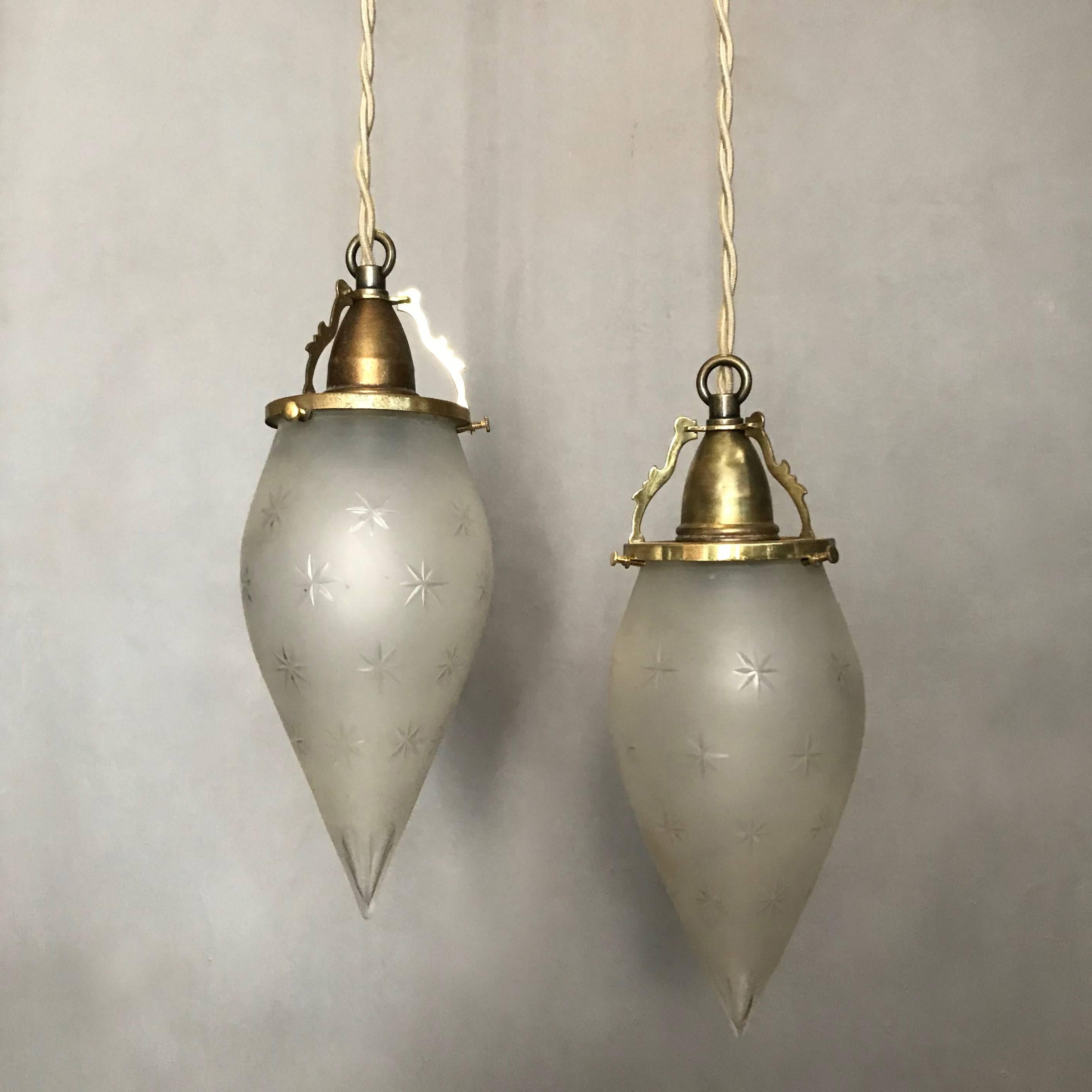 Pair of late 19th century, pendant lights featuring outstanding, 8 inch teardrop shaped, frosted glass shades with etched stars and cut tips with open, filigree brass fitters are newly wired with 36 inches of braided beige cloth cord to accept a 100