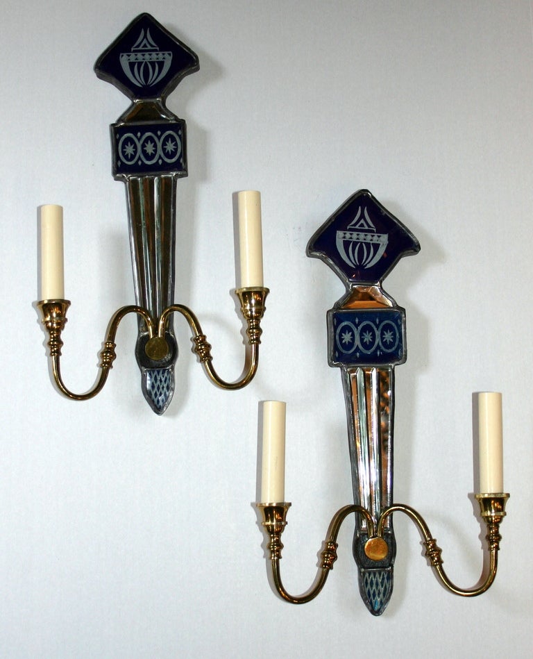 Paire d'appliques à deux bras en miroir, datant des années 1940, en verre bleu peint à l'envers avec des détails gravés.

Mesures :
Hauteur 17.5
