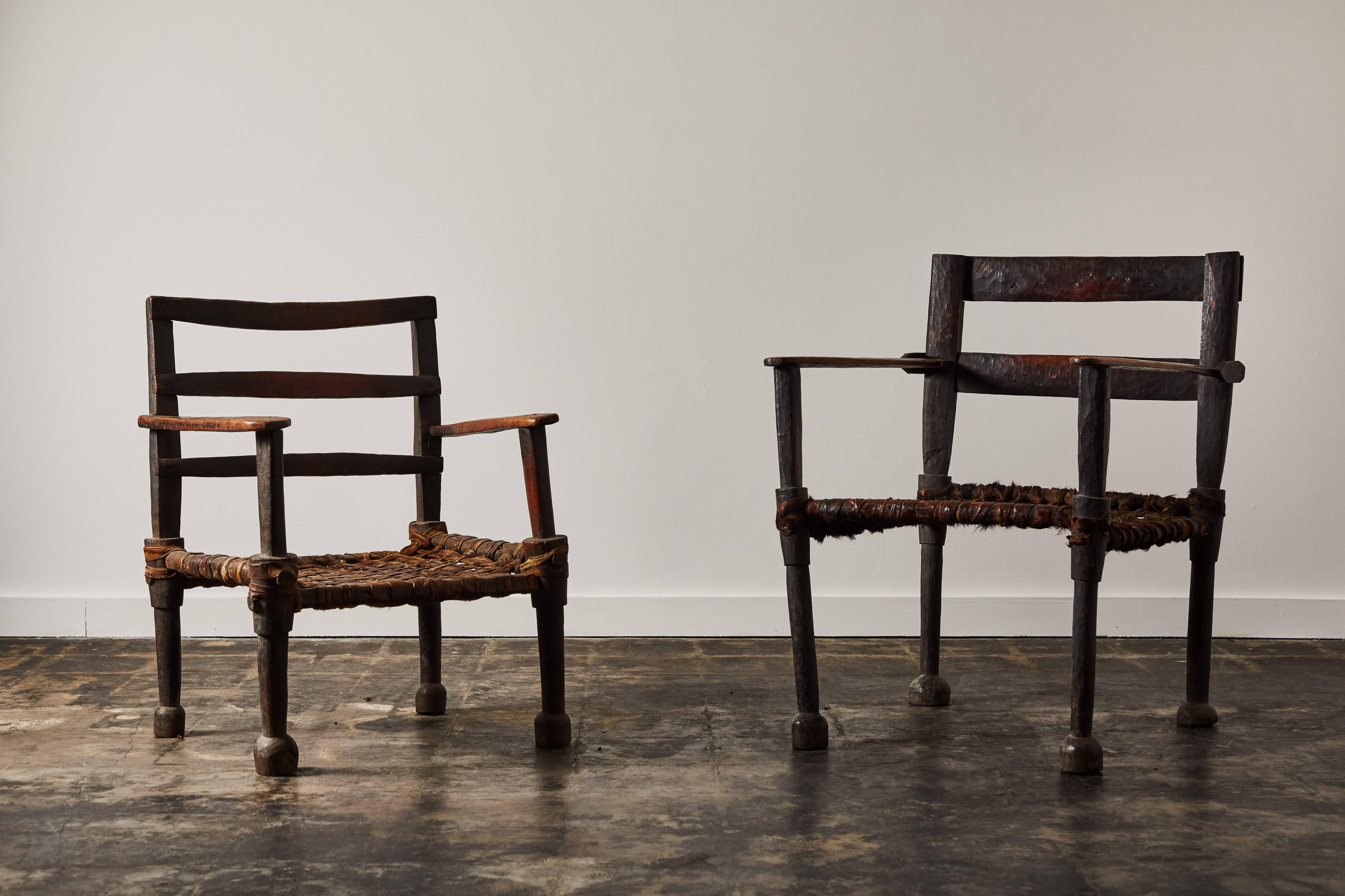 Pair of Ethiopian armchairs with wood and woven hide leather seat. Made in Africa, circa 1940s. Chairs vary in size.

Smaller chair measures 30.5” H x 23.5” W x 20”.