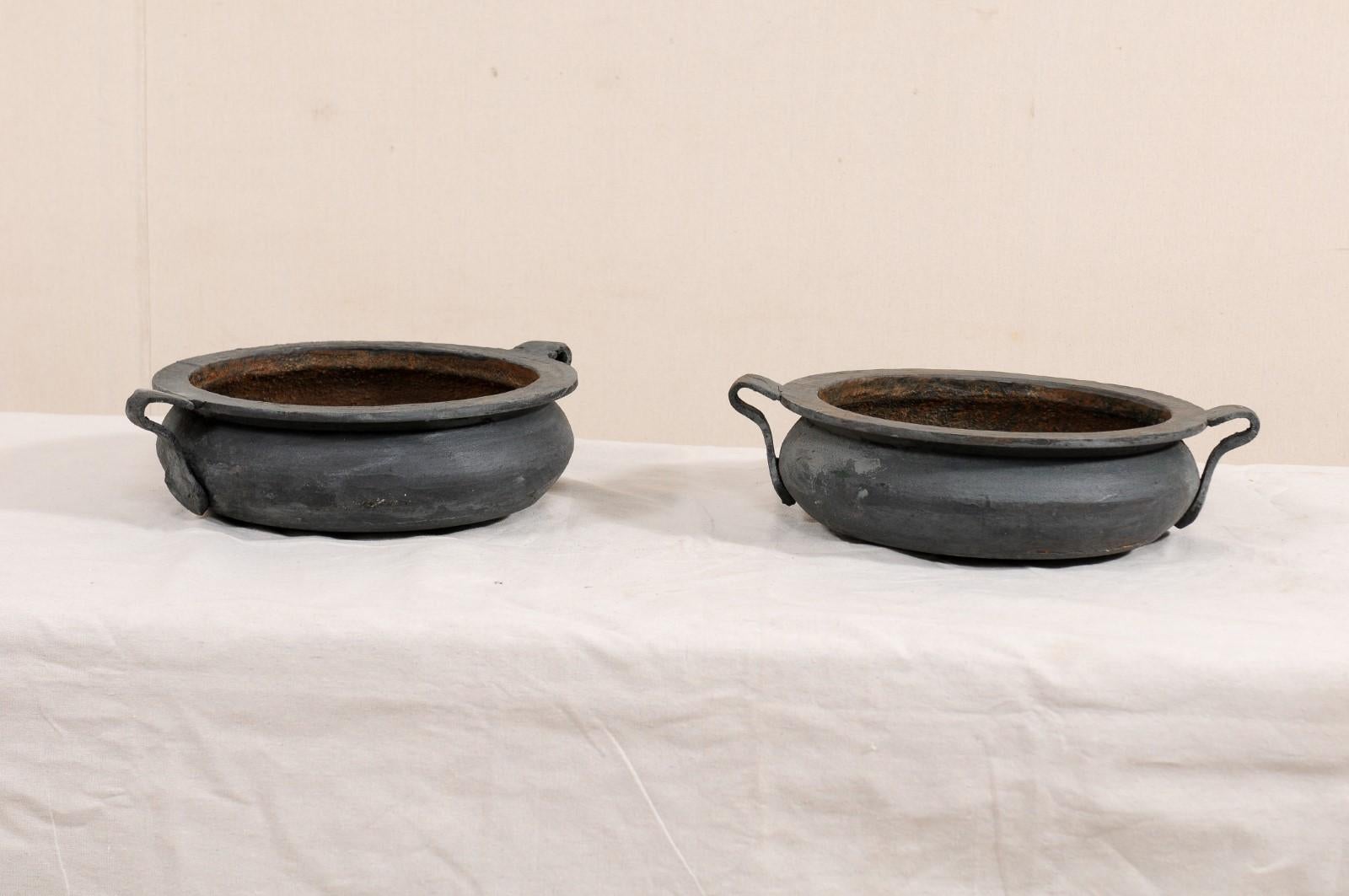 A pair of European cast iron vessels from the early 20th century. This pair of antique bowl planter, from the early 20th century and likely from France, are made from cast-iron and each vessel is circular in shape, shallow in depth, have nice wide