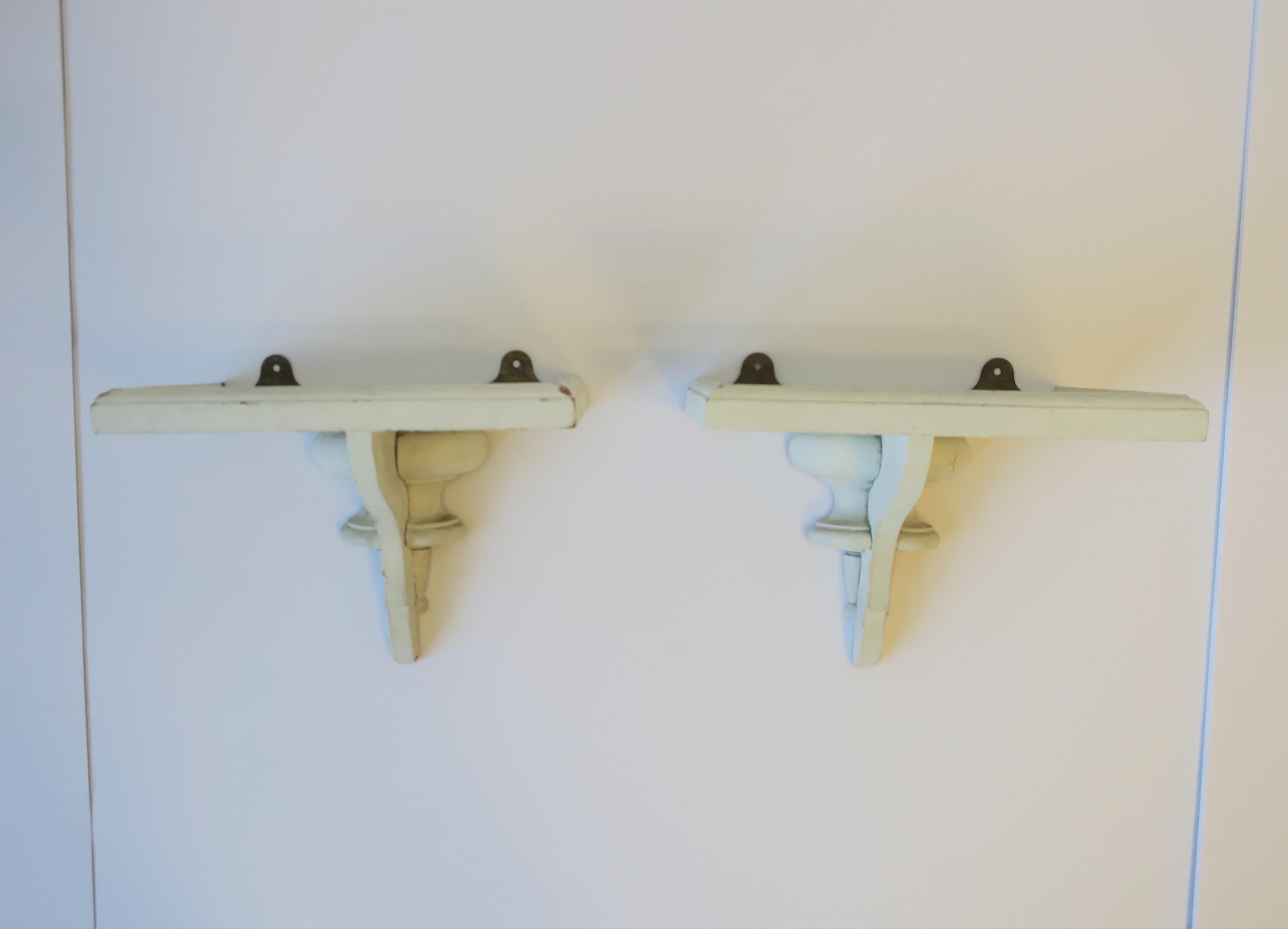 A pair of white painted turned wood wall shelves with gallery edge, circa early-20th century. Set can be used to display vases, sculpture, decorative objects, seashells (demonstrated), etc. Prepared for handing as shown. Dimensions: 7.13