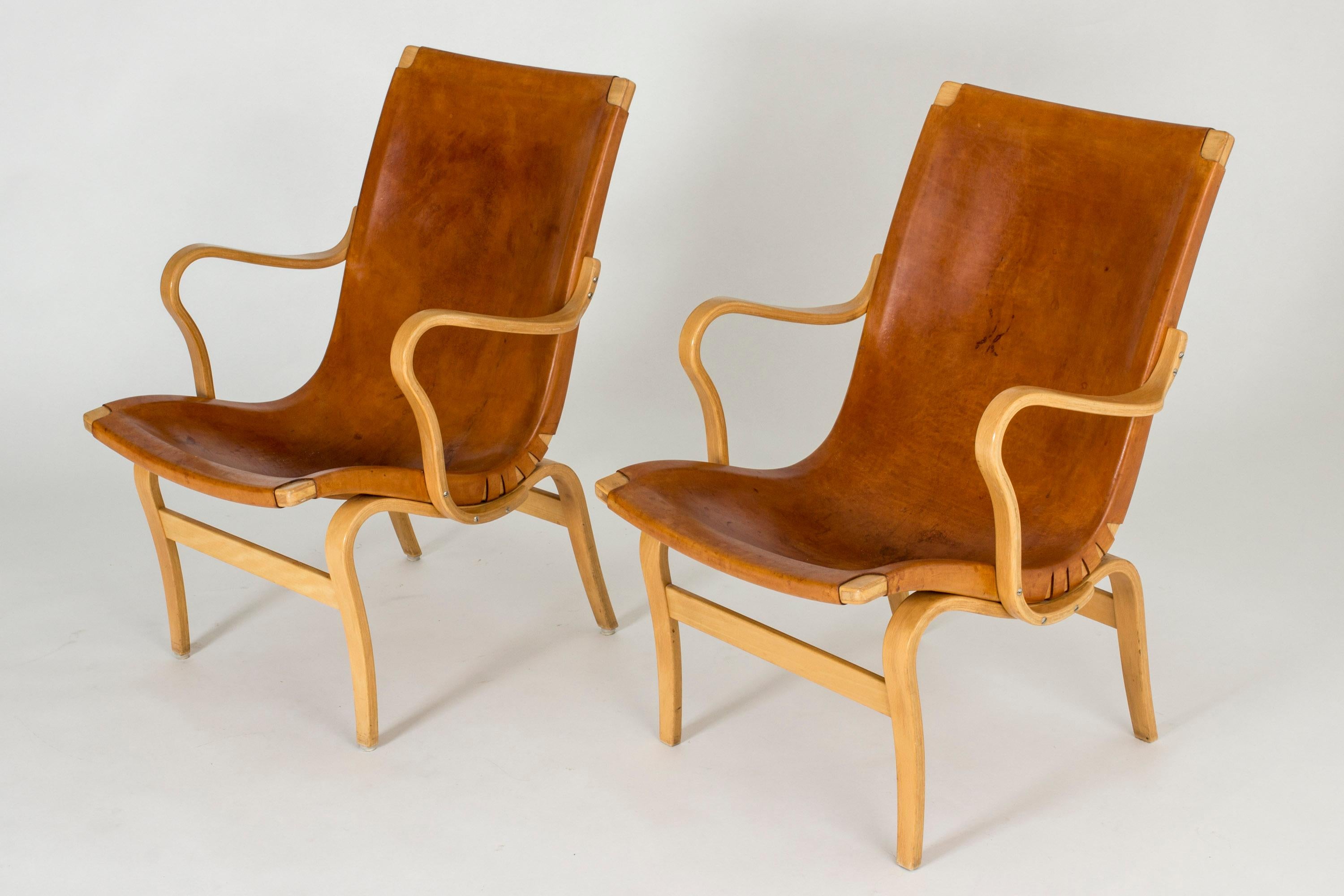 Pair of lovely “Eva” lounge chairs by Bruno Mathsson, with leather seats on beech bentwood frames. Beautifully patinated natural colored leather.

  
