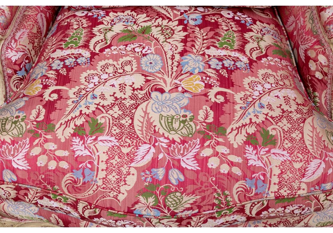 Paire de Bergeres françaises très bien faites et solides, tapissées sur mesure de tissu floral et feuillu rose, vert, or et tan. Les chaises sont dotées d'un cadre sculpté et à volutes, sculpté de façon complexe et volontairement abîmé pour révéler