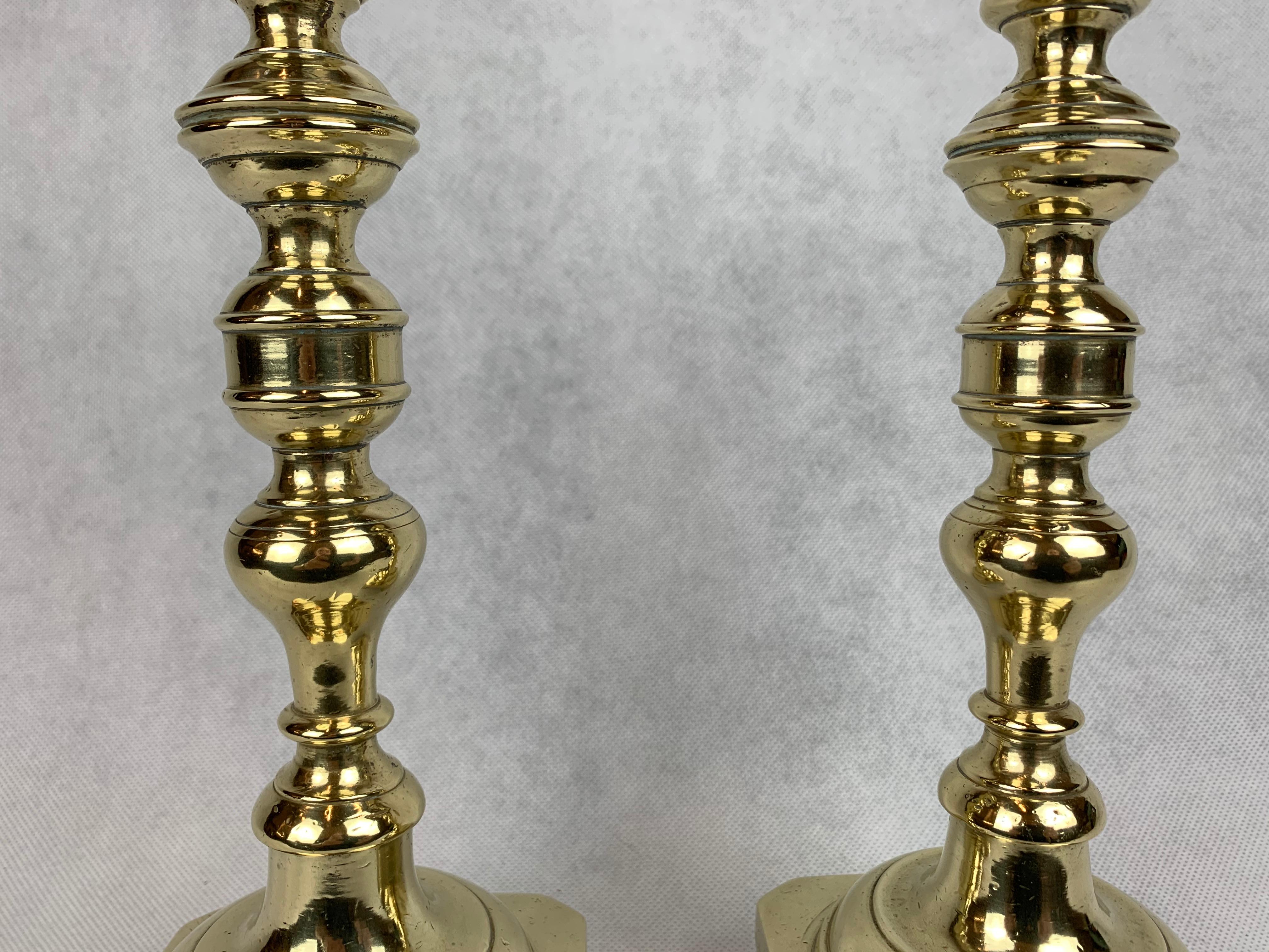 Exceptional fine pair of solid brass Russian candlesticks. The candleholder is in a flared vase form, while the base is banded, square and footed. If you turn the candlesticks around you can see the massive turned screws for disassembly and