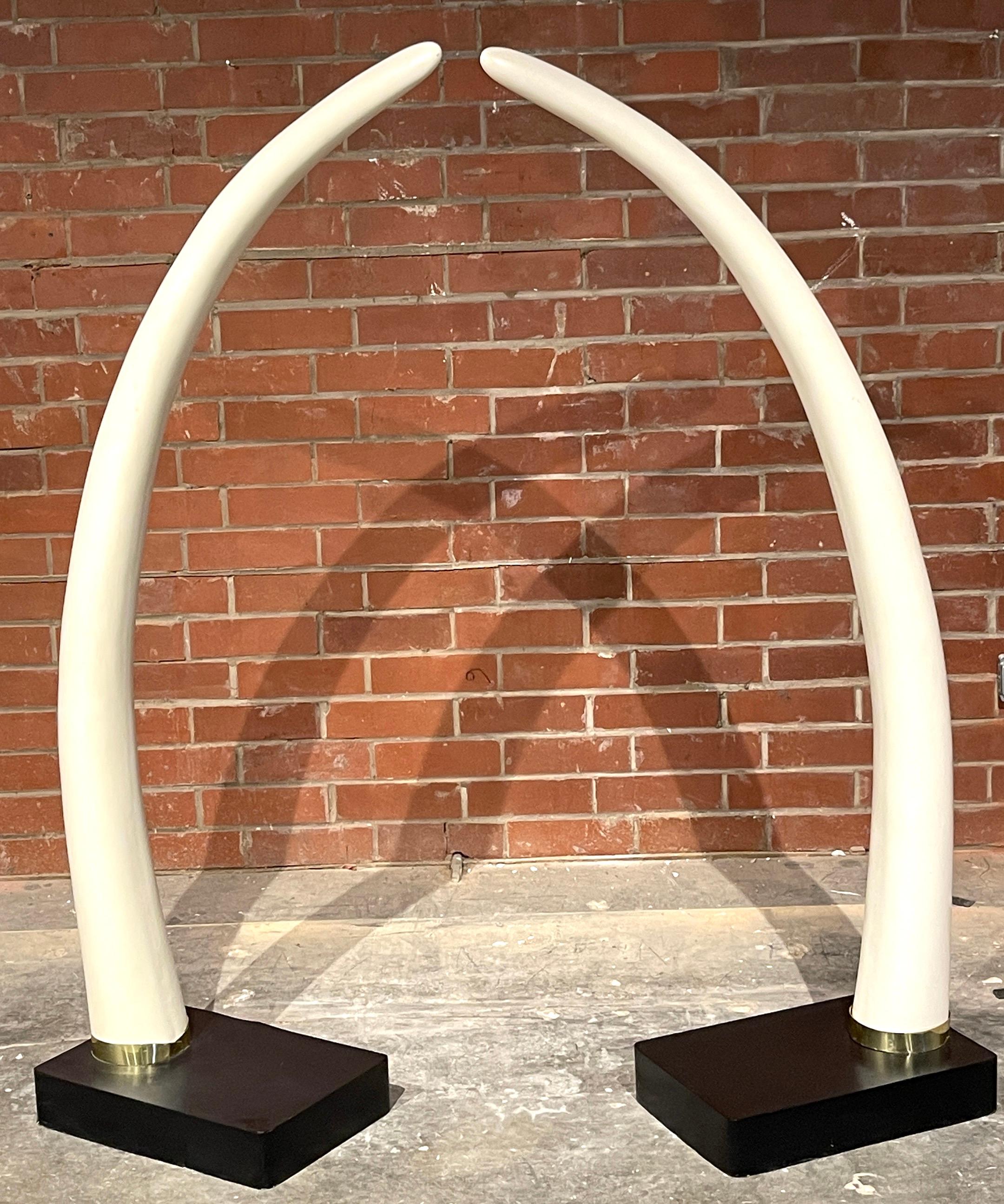 Pair of Exotic mid century lacquered faux elephant tusk sculptures 
USA, Circa 1980s

Of large scale, each one a realistically modeled tusk, mounted with brass collars on a ebonized wood pedestal base. Ready to place.




