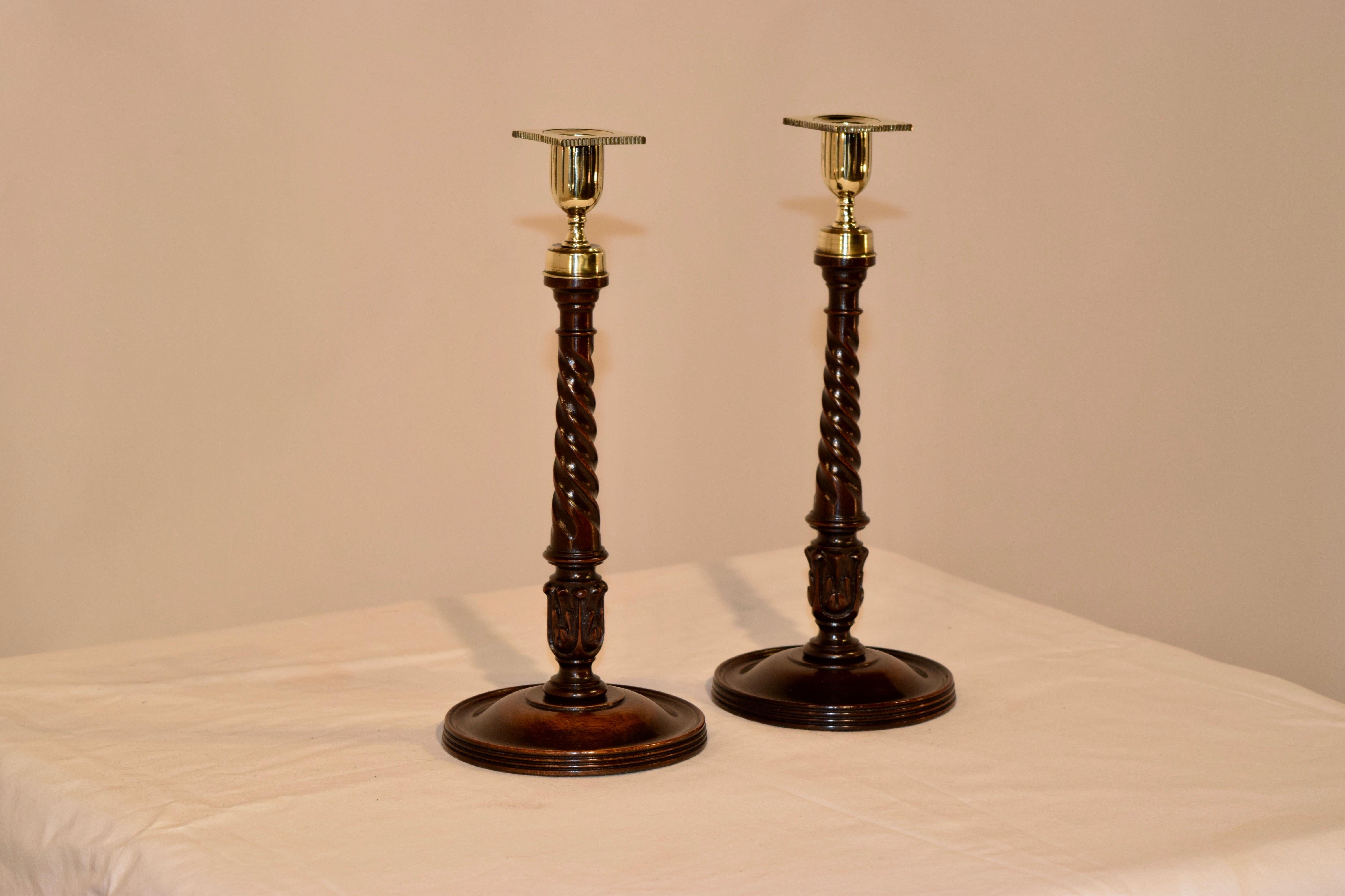 Pair of exquisite 19th century mahogany candlesticks from England. They retain the original hand-turned and hand cast brass candle cups and bobeches, following down to stems which are also hand-turned with a ribbon twist and wonderfully hand carved