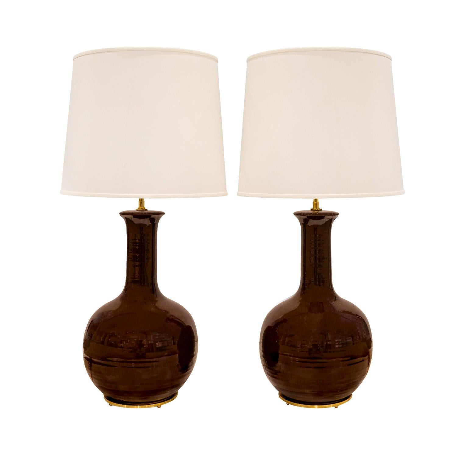 Pair of fine artisan porcelain table lamps with custom polished brass hardware and bases with ball feet, American 1960's.  There are subtle undulations in the body of the lamps.  These are hand-thrown and beautifully made.  Brass has been polished