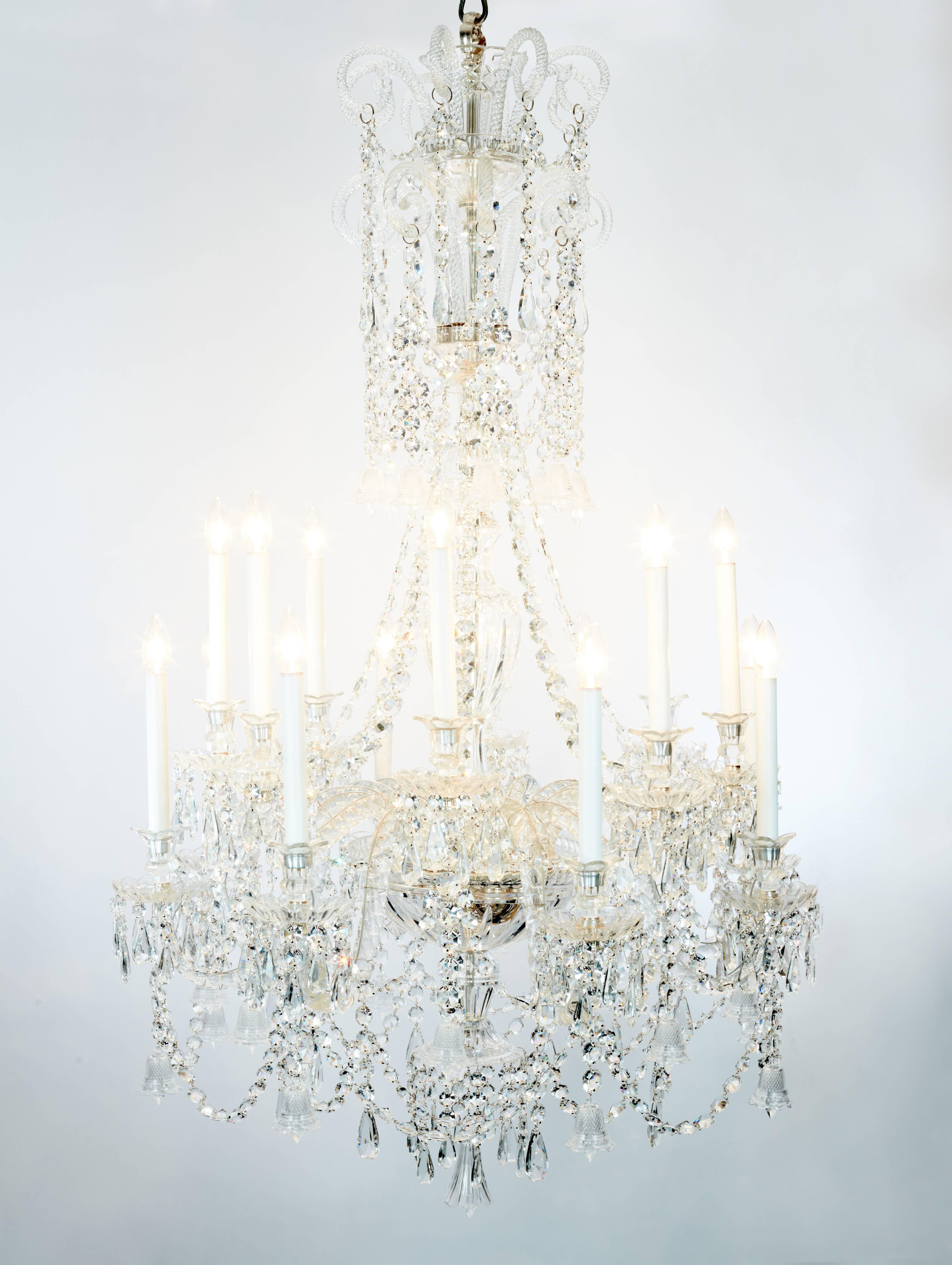 A pair of beautiful Baccarat chandeliers with 16 twisted arms each terminating in a crystal bobeches and recently rewired candle bulb holder. Each arm is linked with crystal drops and crystal bells. The crown features barley twists with cascading