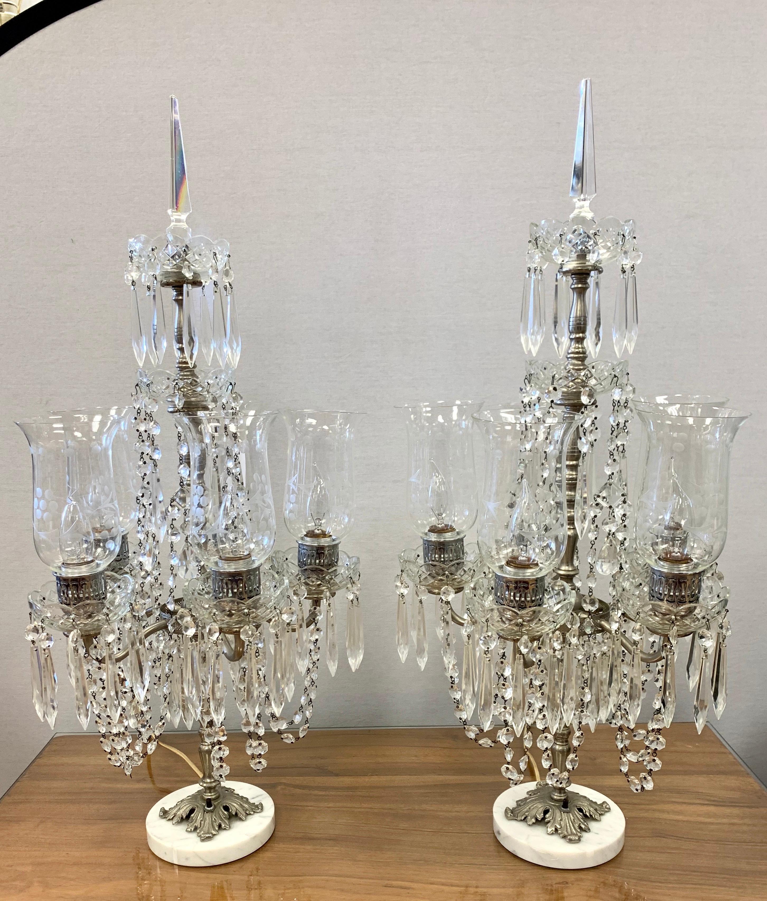 This exquisite pair of five arm candelabras make quite a statement. They feature multiple floating prisms and dangling crystal chains and a large pointed obelisk at the top. Beautiful etched hurricane glass over each light.  They are supported by