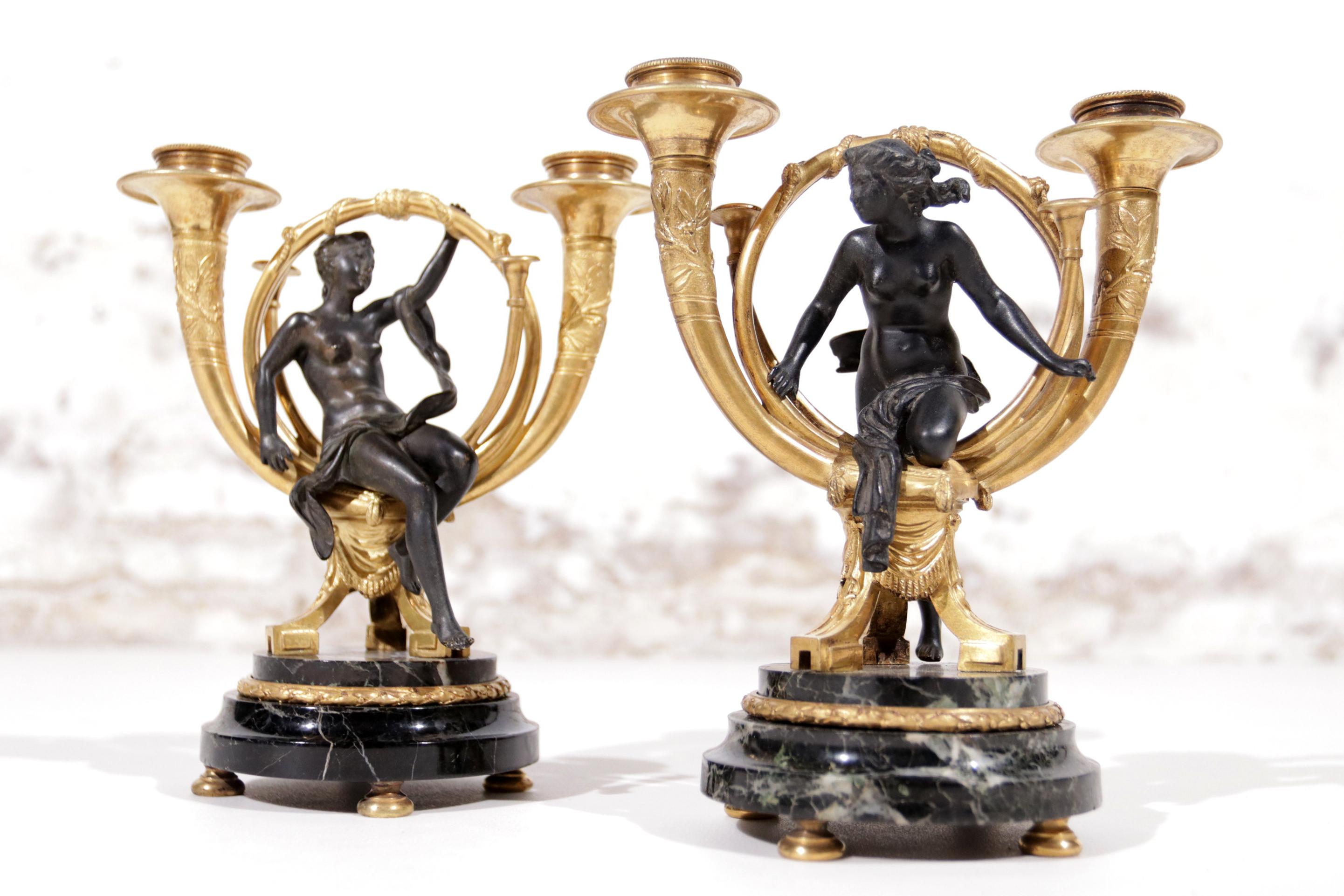 These candlesticks are ornate artifacts from the French Empire period, which dates back to the early 19th century, typically considered as the reign of Napoleon I from 1804 to 1814. This era is known for its classical designs and motifs that often
