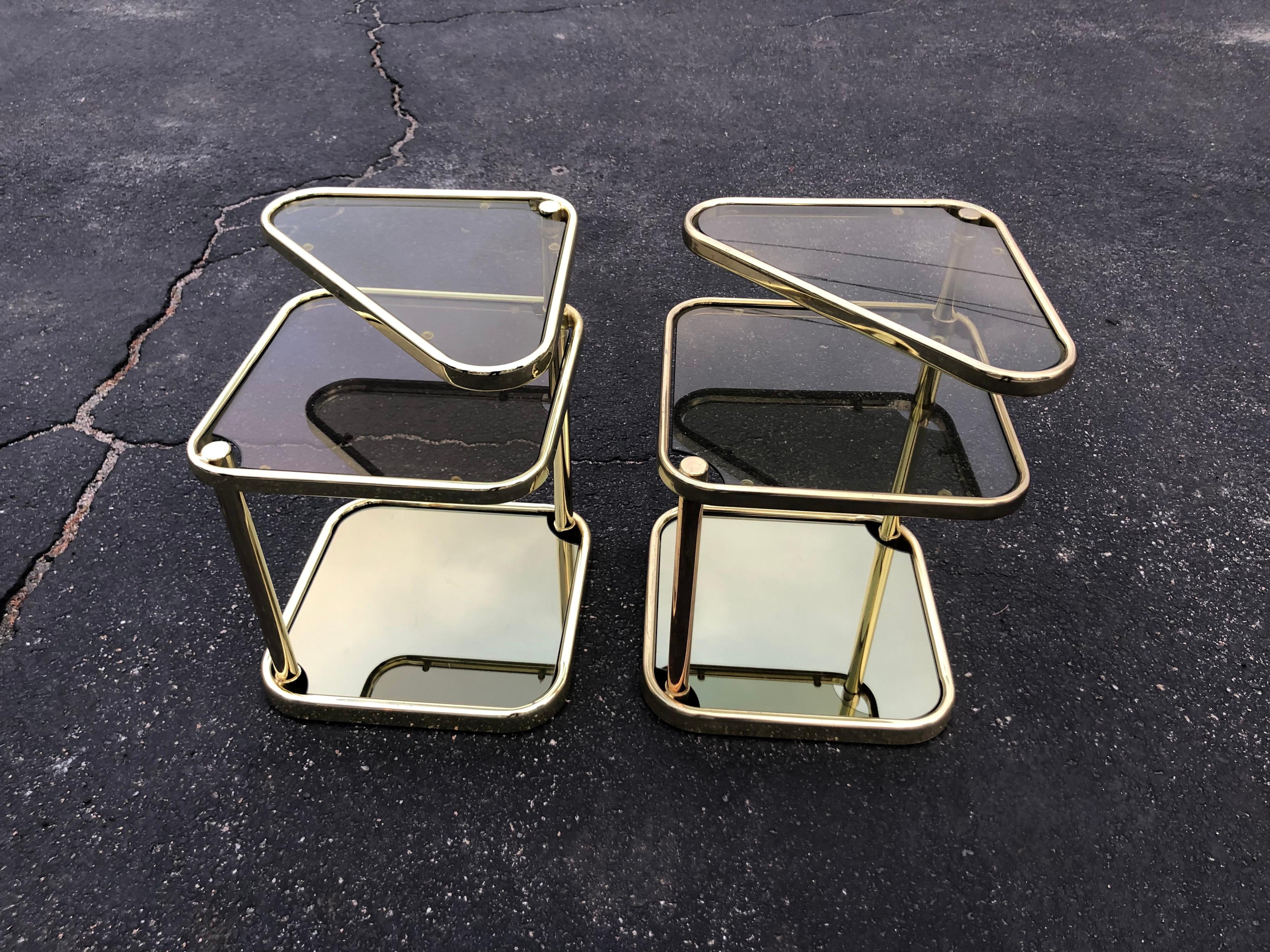 Pair of extendable three tier brass and smoked glass tables. Geometric traingular shape. Matching coffee table also available. Post modern 1980's design. When fully extended it measures: 30