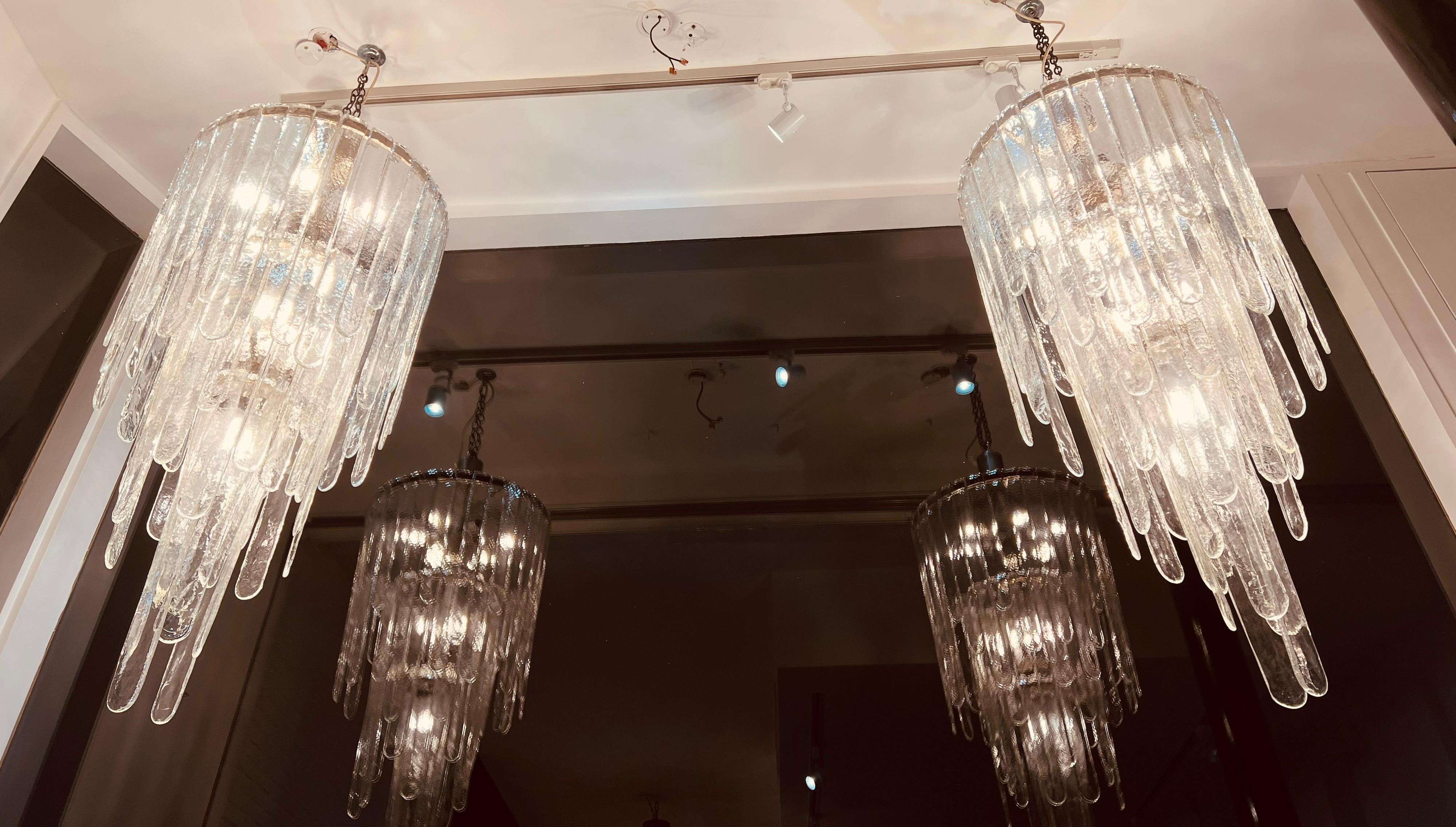 An outstanding pair of extra large mazzega chandeliers with 10 bulbs fittings on each supported by a chrome structure. Each chandelier contains 60 alternate size hand blown Murano glass that allows them to extend to 130cm from the ceiling cap with